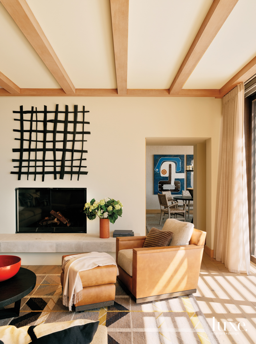 A woven, black artwork hangs over the fireplace in the living room.