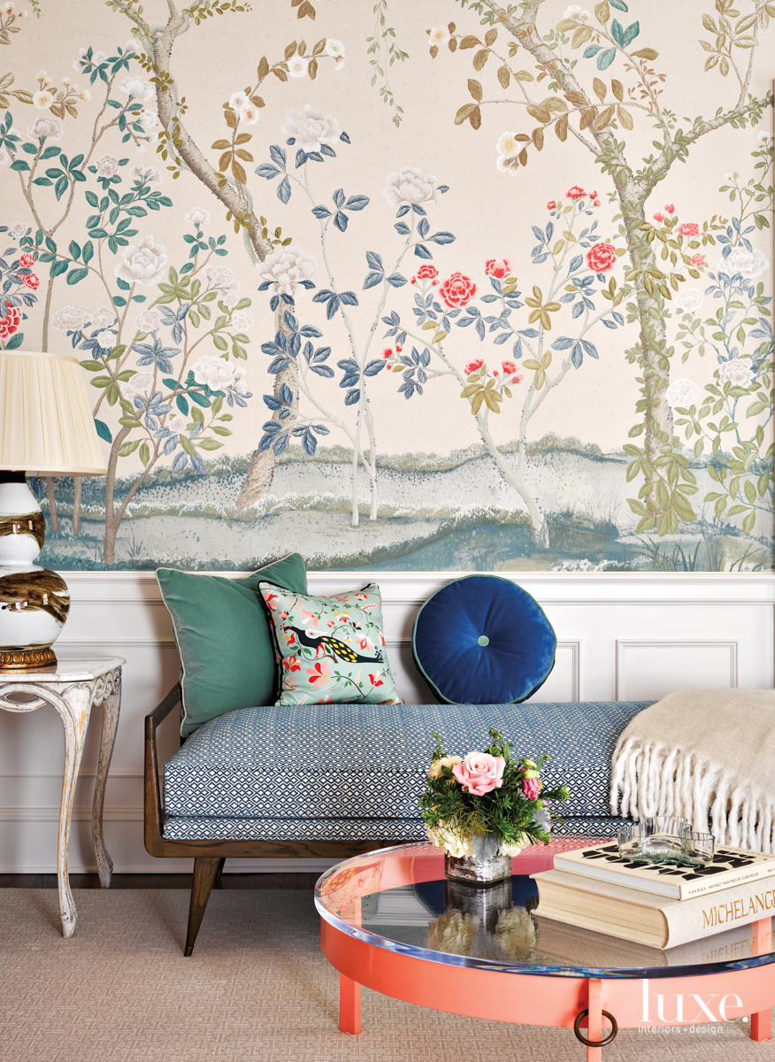 living room with flower and tree wallpaper, daybed with blue and green pillows and peach colored round table