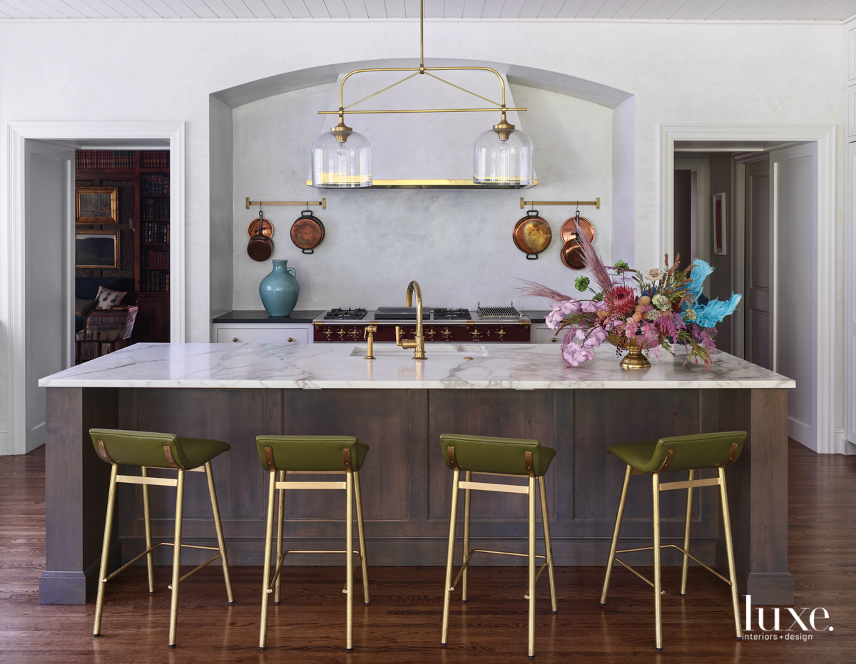 kitchen with green and brass barstools, marble countertops and a brass light fixture
