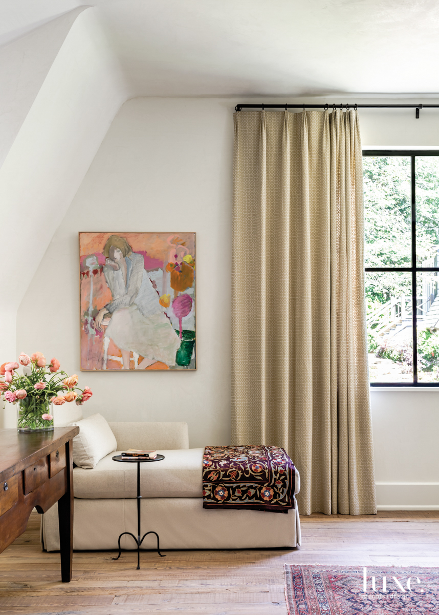 bedroom vignette featuring a large window, chaise lounge and abstract painting