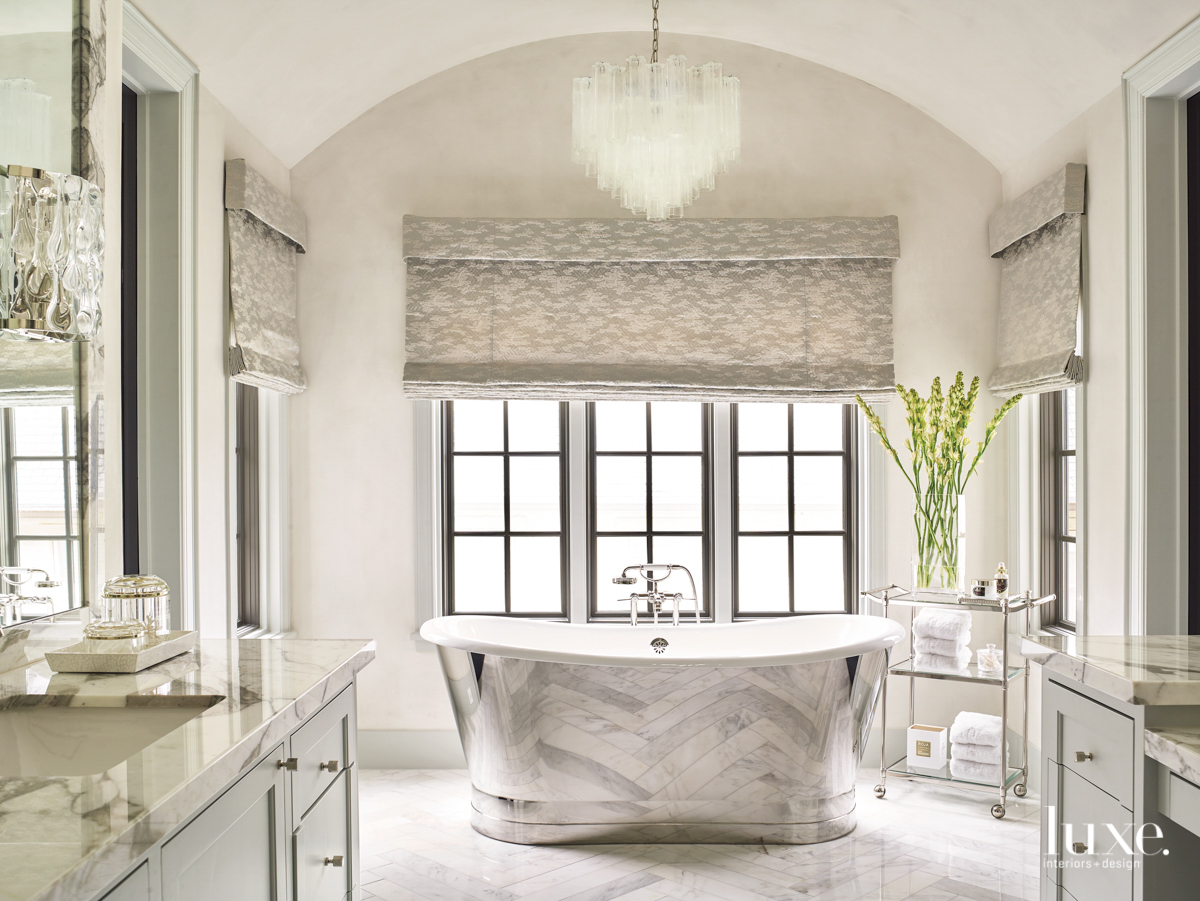 master bathroom featuring a glass chandelier and lined roman shades