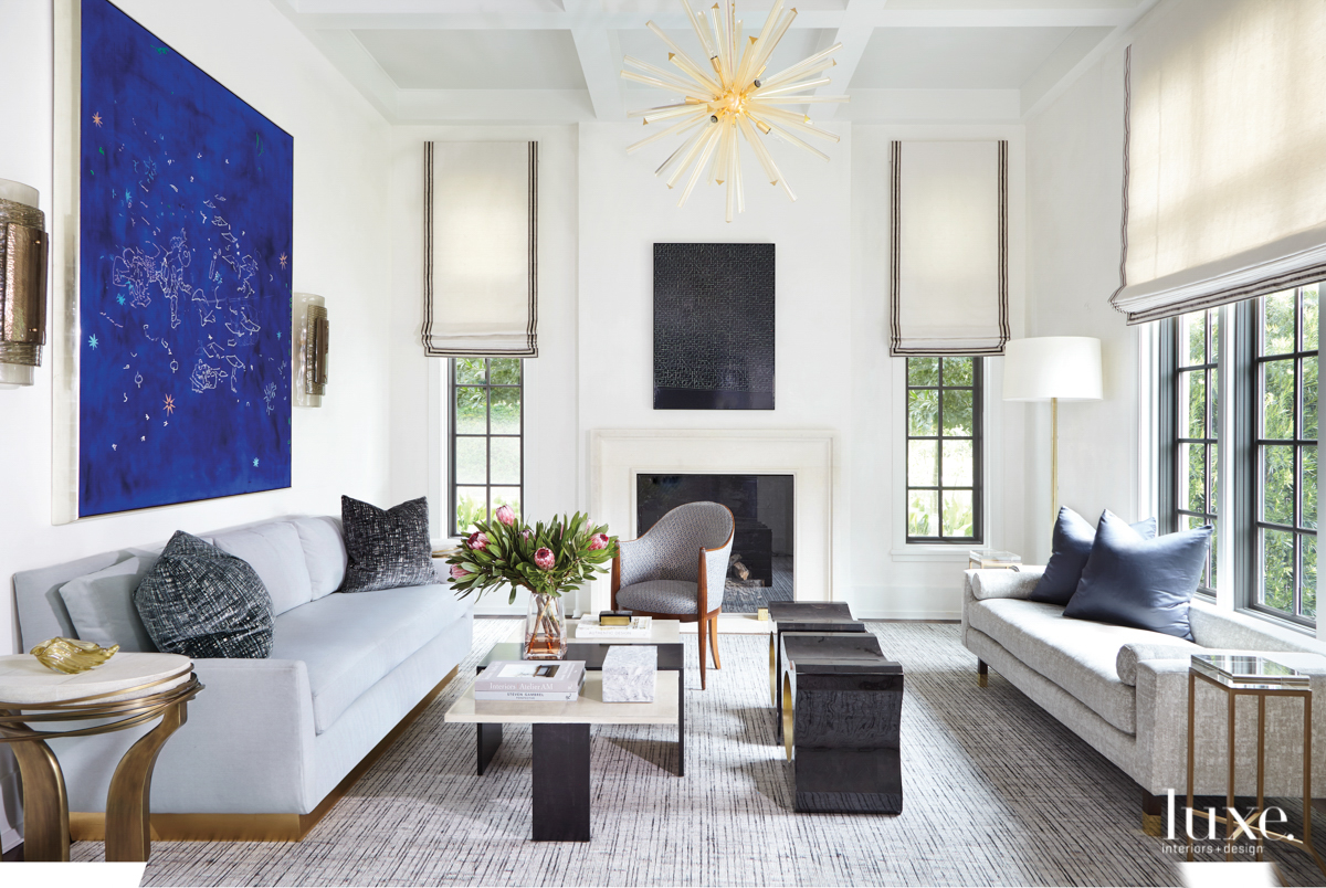 living room with two sectionals, bright blue art, and chandelier