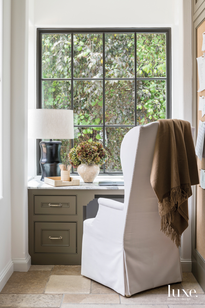 work space in a nook featuring large windows and high-back wing chair