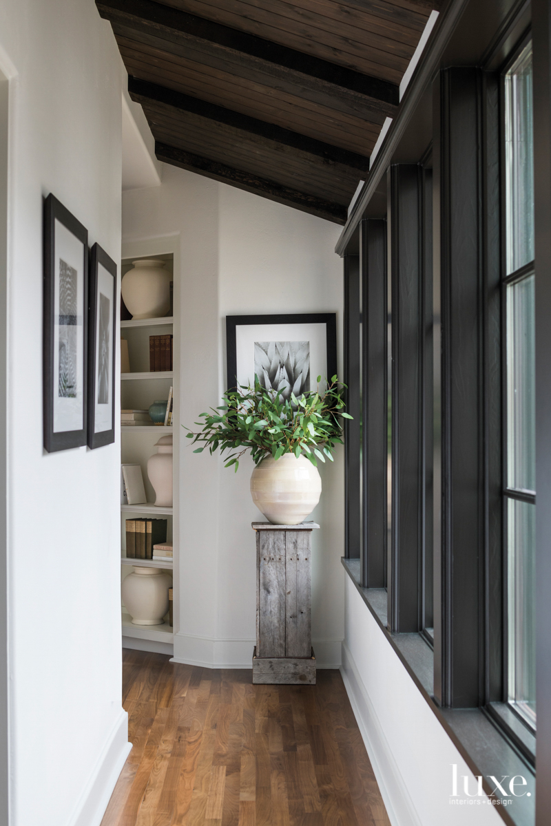 grand opening with floor to ceiling windows featuring a wooden column and plant atop it