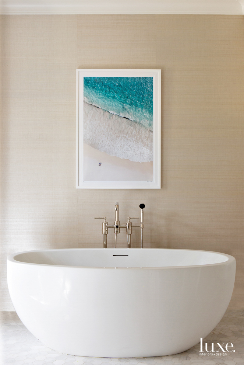 Serene master bathroom with freestanding tub and Gray Malin photography