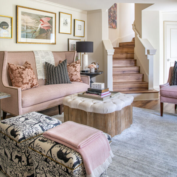 A pink-and-blue-pastel hued family room at the foot of a staircase in home.