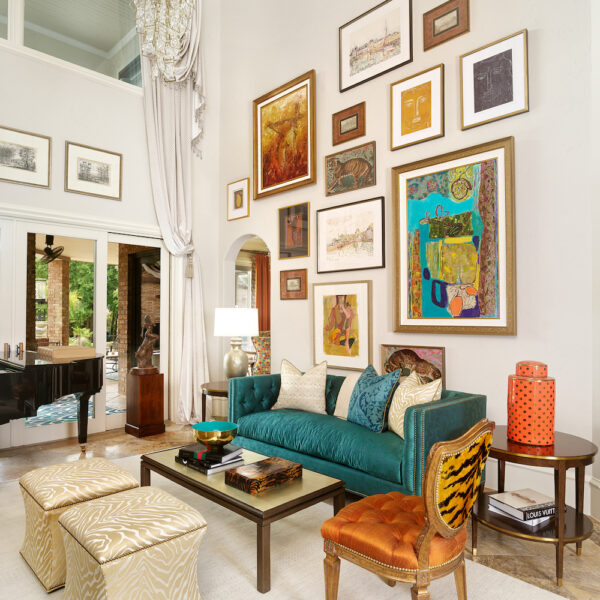 Blue, orange, and white colored art gallery wall above turquoise sofa