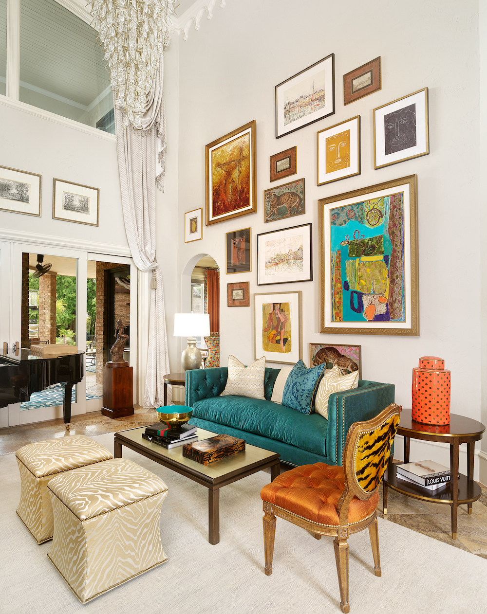 Blue, orange, and white colored art gallery wall above turquoise sofa