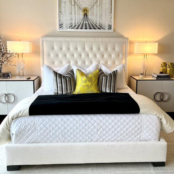 Cream tufted headboard and bed framed with white and gold accent end tables