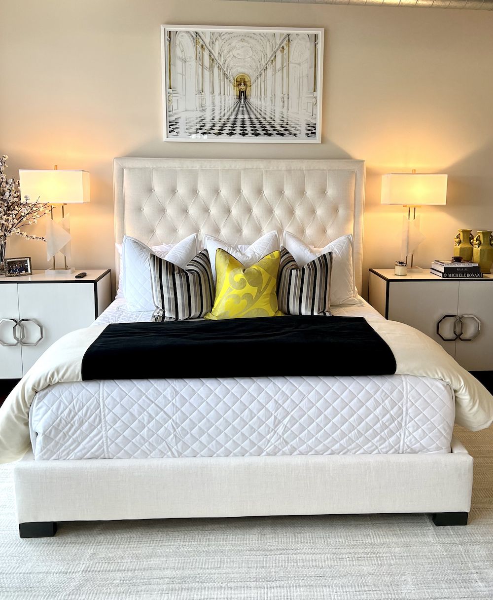 Cream tufted headboard and bed framed with white and gold accent end tables
