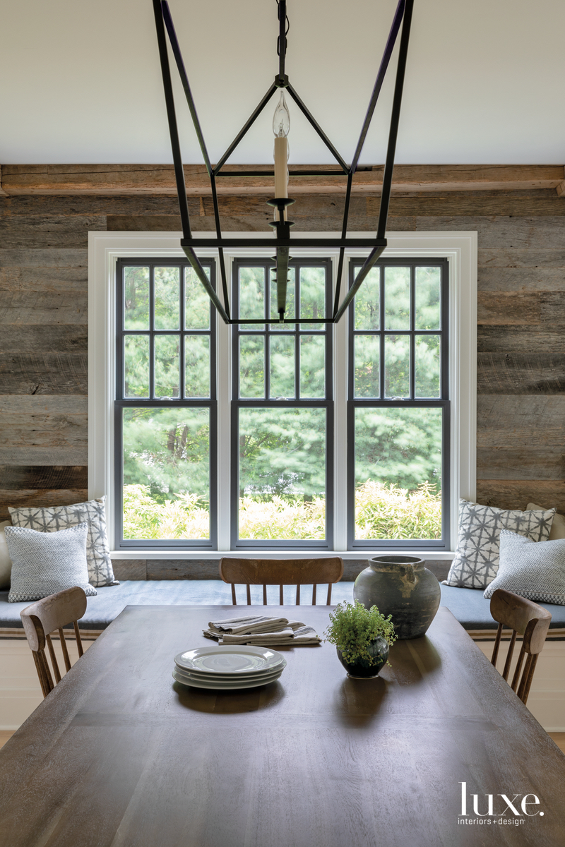open breakfast nook with shiplap walls, wooden table and sculptural chandelier