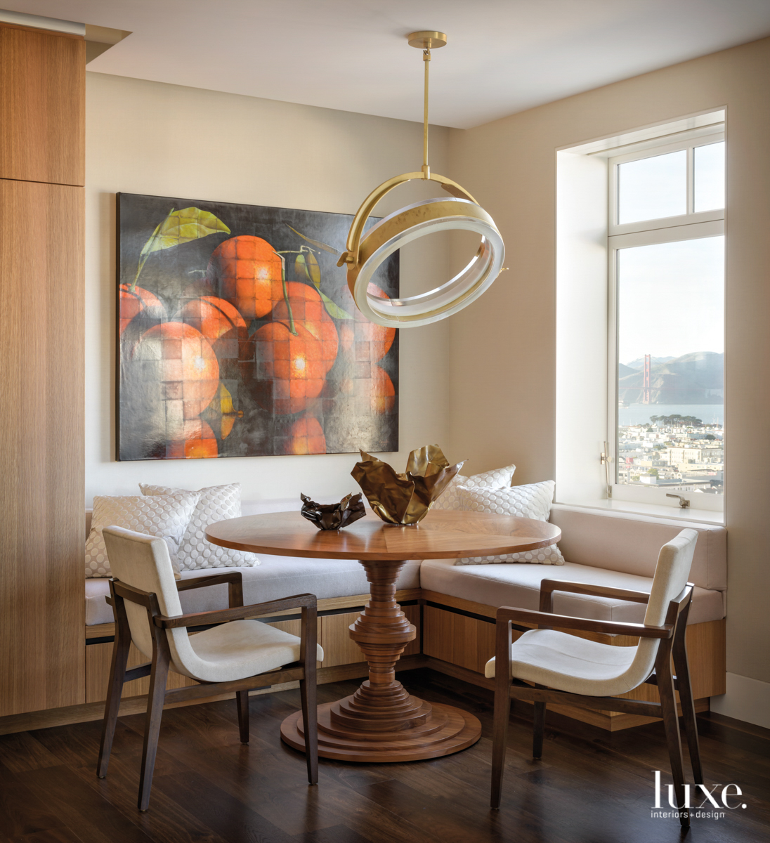 cozy breakfast nook with round table, white chairs and artwork of oranges
