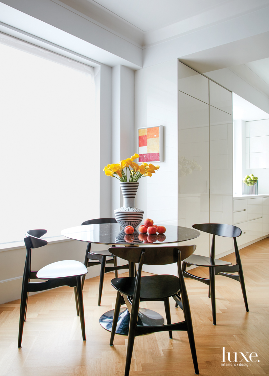 breakfast nook with sleek black matte table and chairs, with yellow daffodils in vase