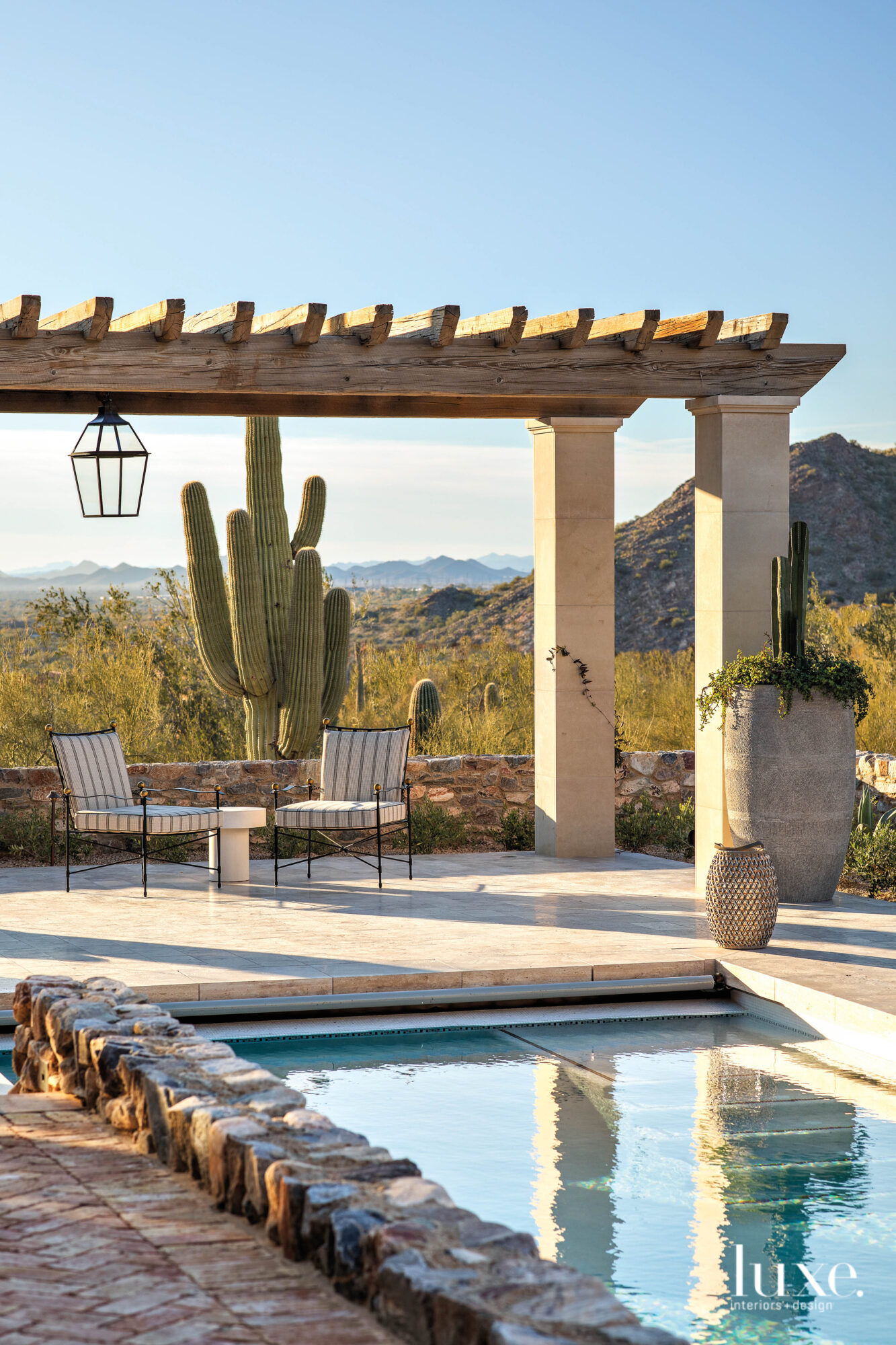 A cactus and a stunning mountain view sit poolside in the backyard