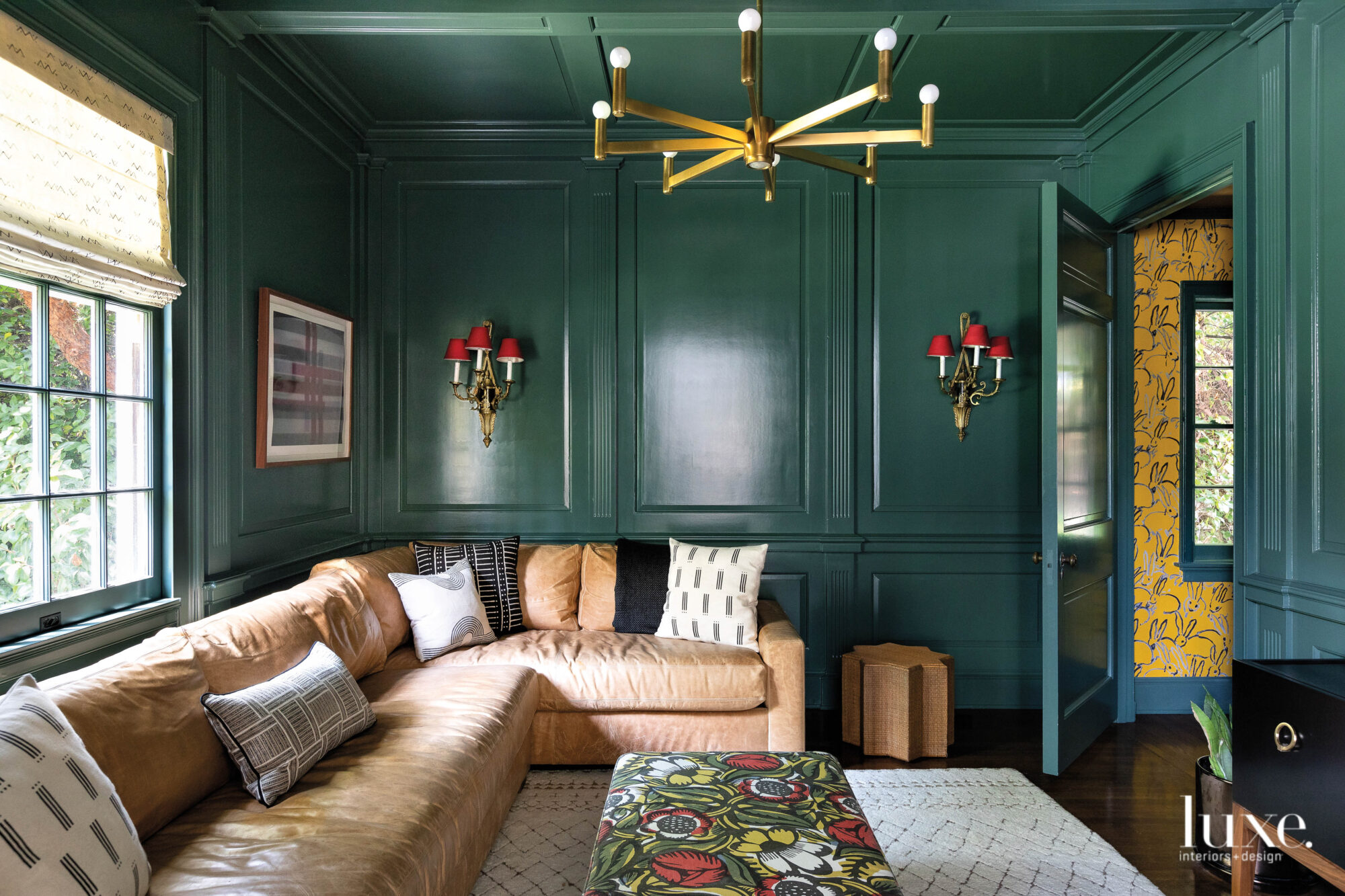 A den shows contrasting colors with dark green walls and a neutral toned couch.