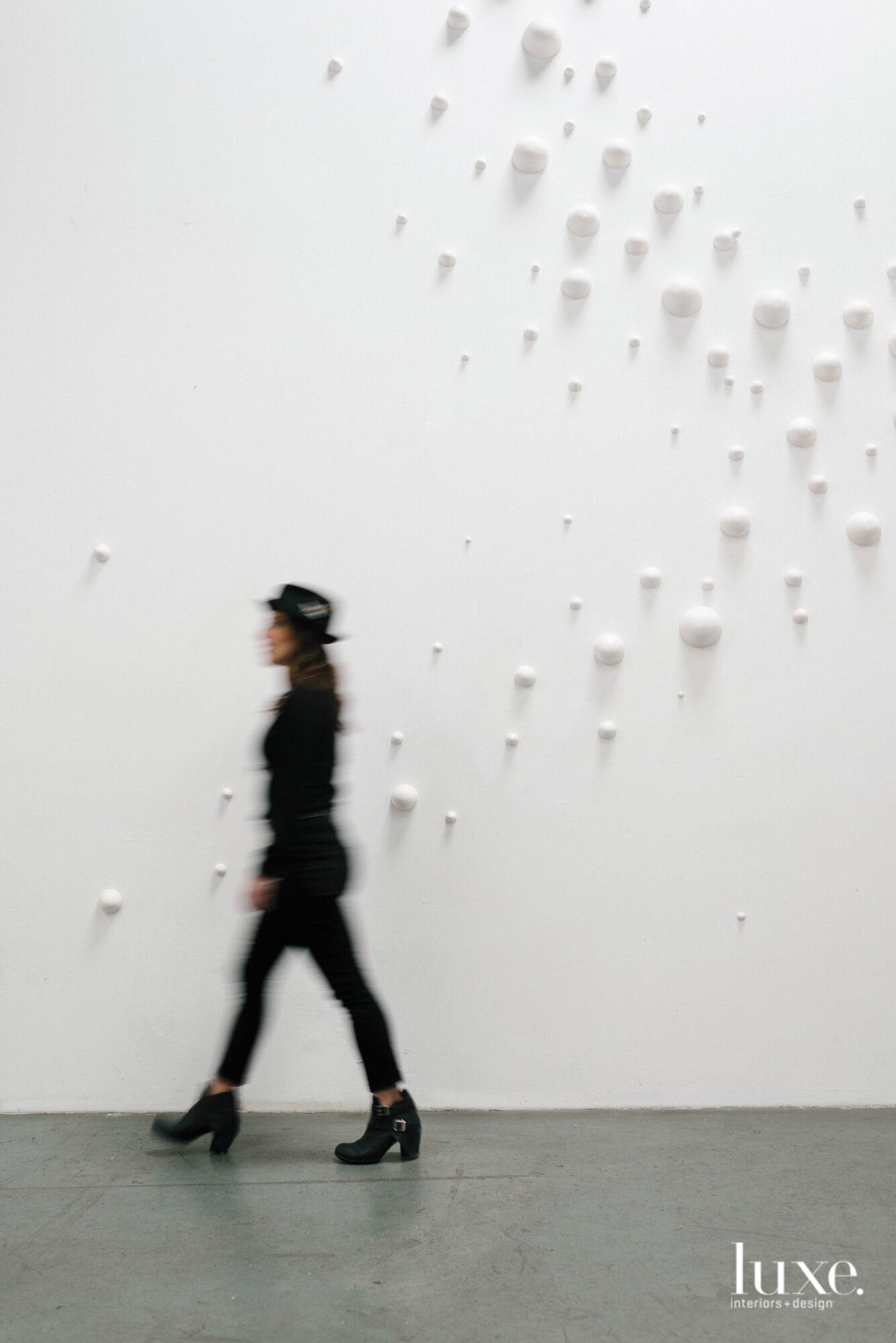 Artist Elizabeth Orleans walking by a white ceramic installation