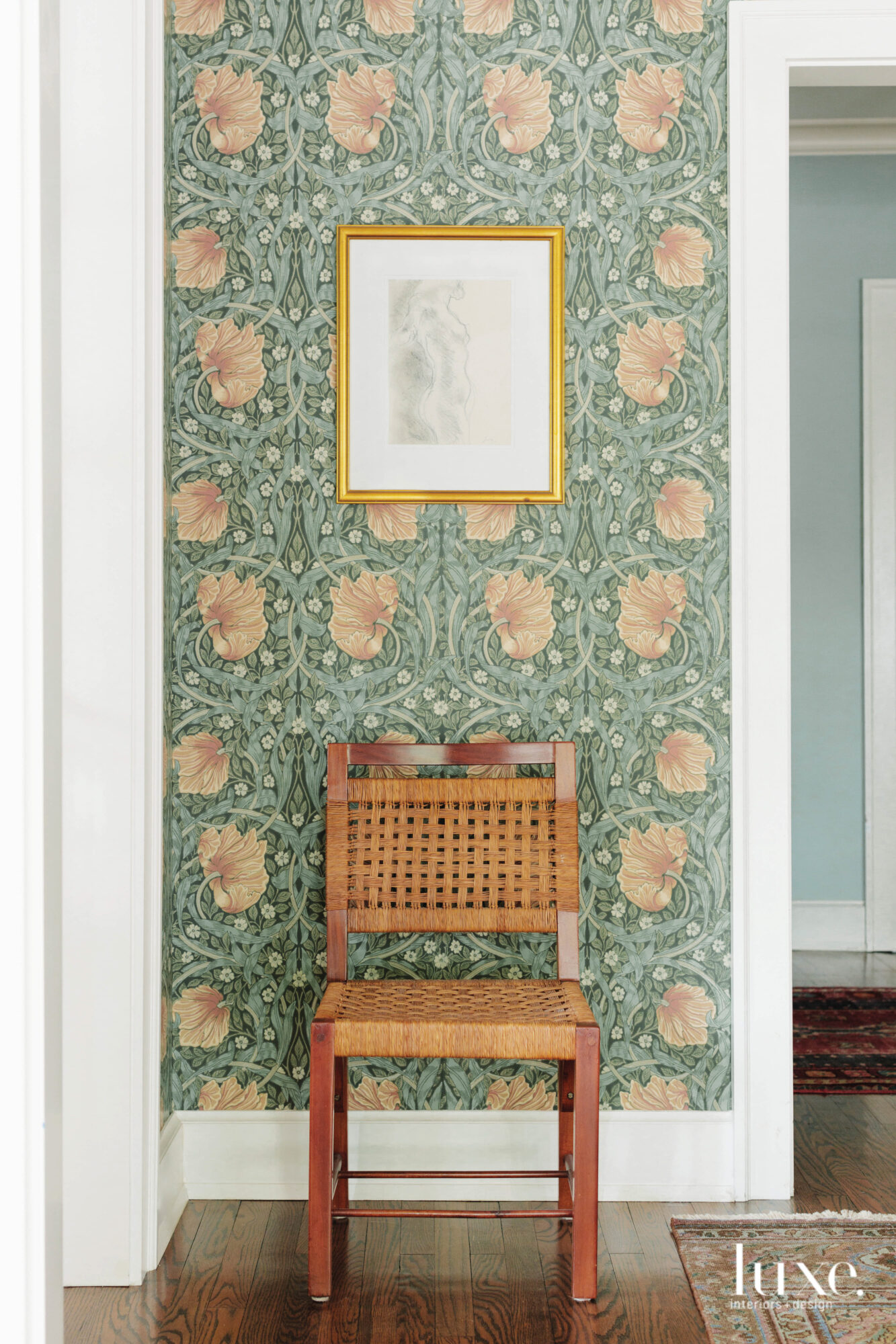 A vintage chair complements the moss green wallpaper of the dining room