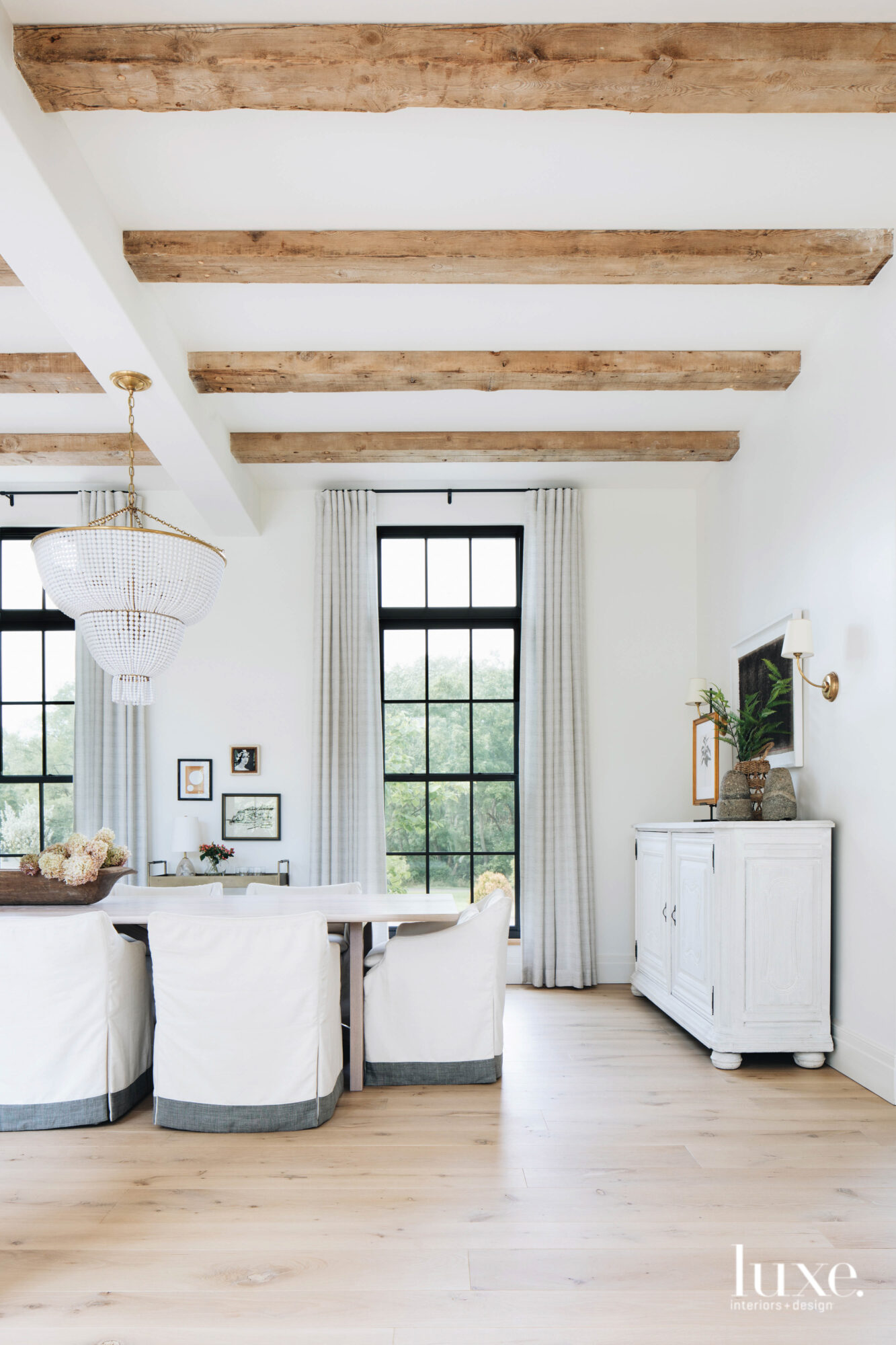 Rough wood beams add a rustic touch to this all-white dining room.