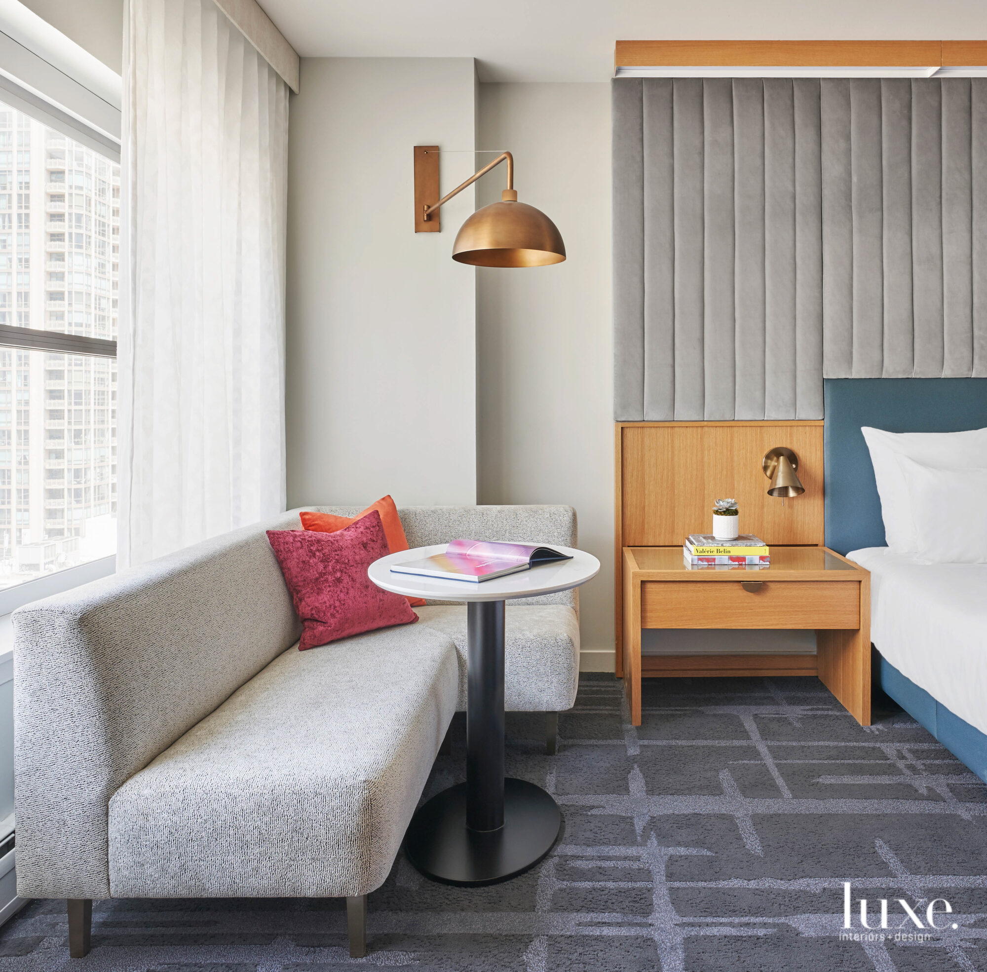 Colorful pillows, golden light fixtures and a blue bed frame make this bright hotel space pop. 