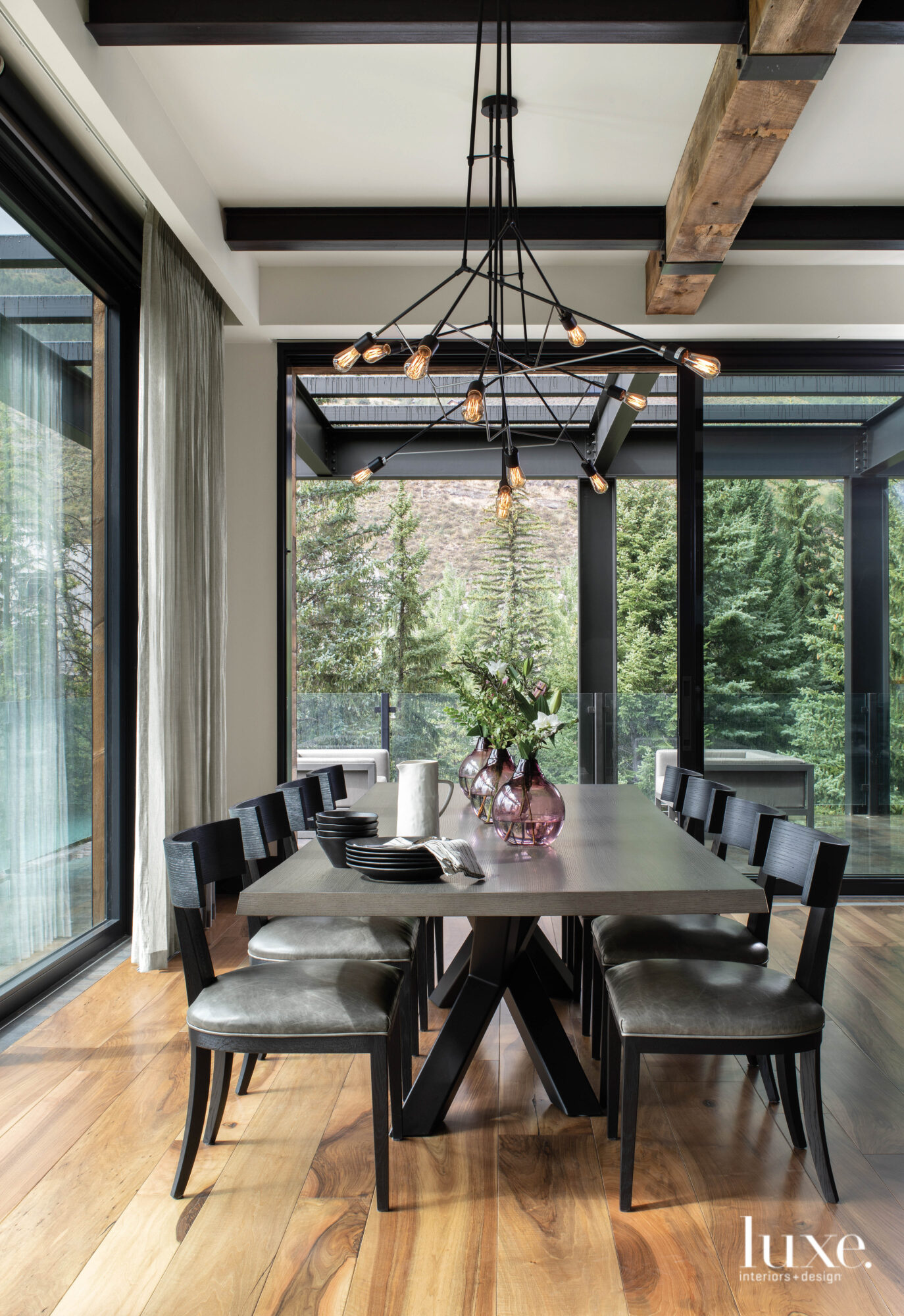 A dining room has a large table and a branch-like chandelier
