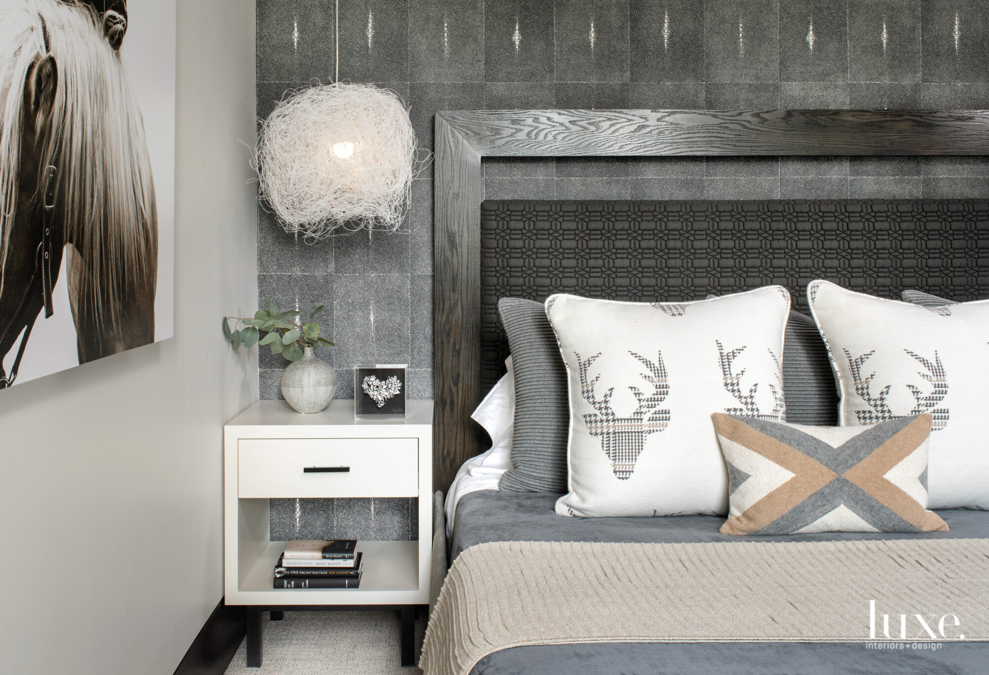 A bedroom has pillows with an deer-head motif and a sculptural light fixture.