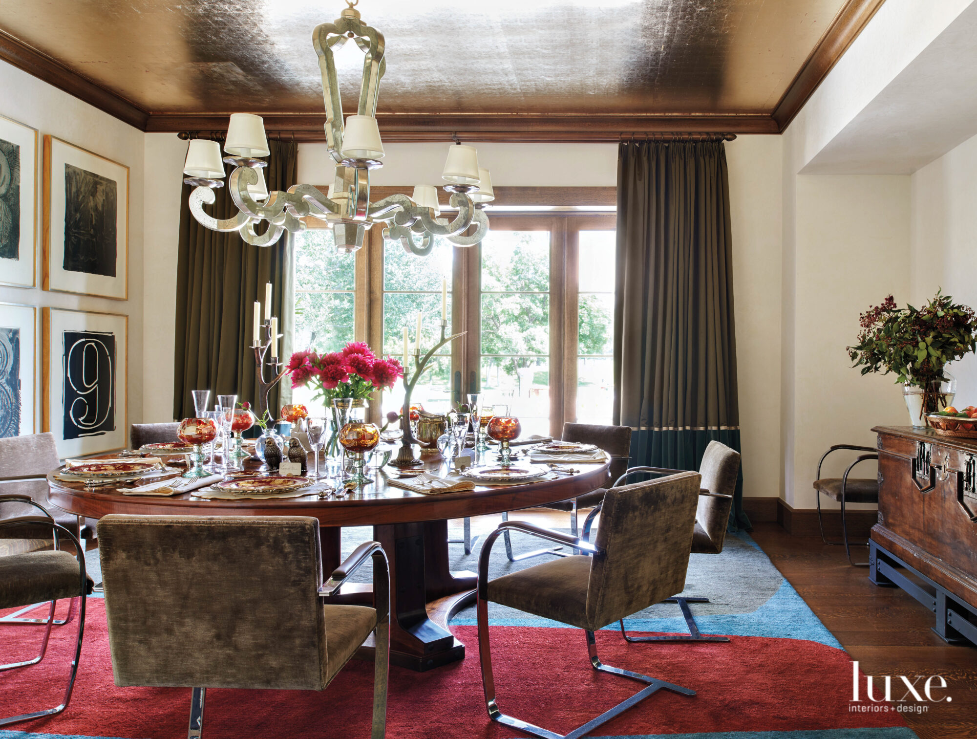 The dining room features a round table, modern chairs and a gilded ceiling.