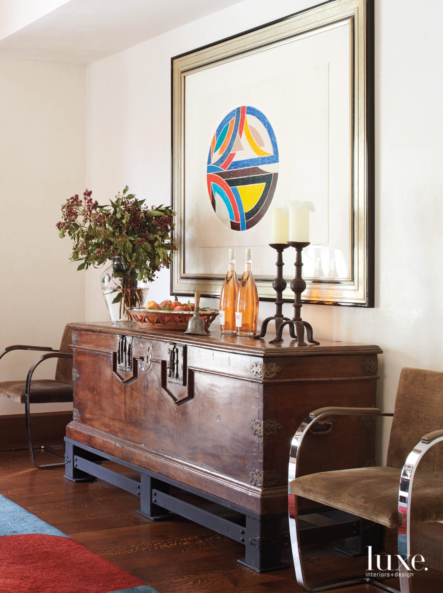 A dining room features an antique chest and modern art at one end of the room.