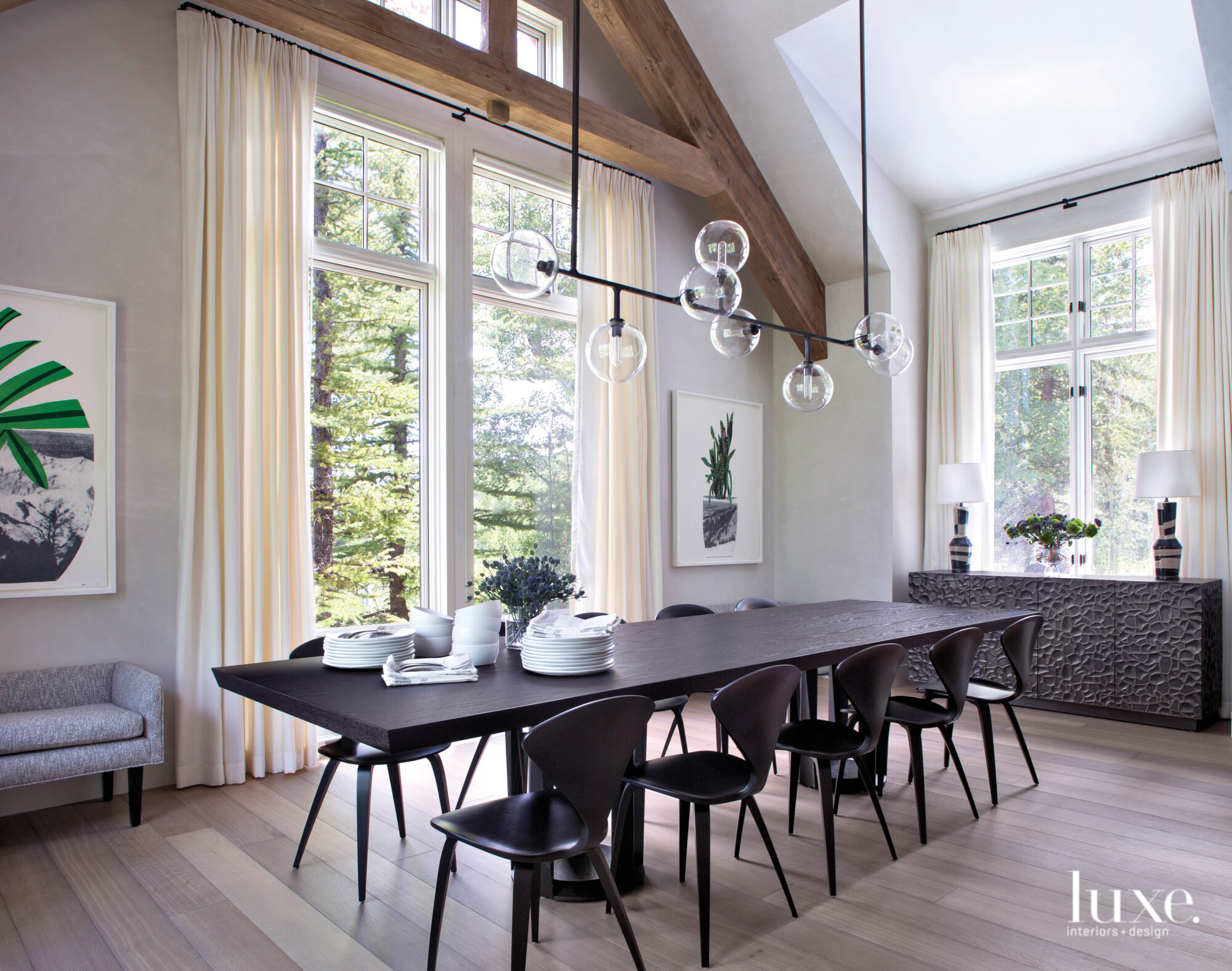 A dining room has a dark table and a linear chandelier overhead.