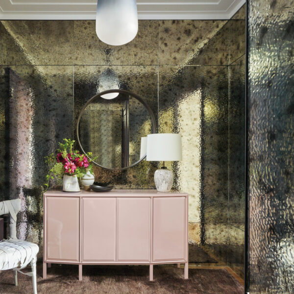 Start Spreading The News: A Space Can Be Both Edgy And Elegant, And This NYC Apartment Is Proof An antique, reflecting wall welcomes all who enter the apartment; a pink cabinet sits facing the door.