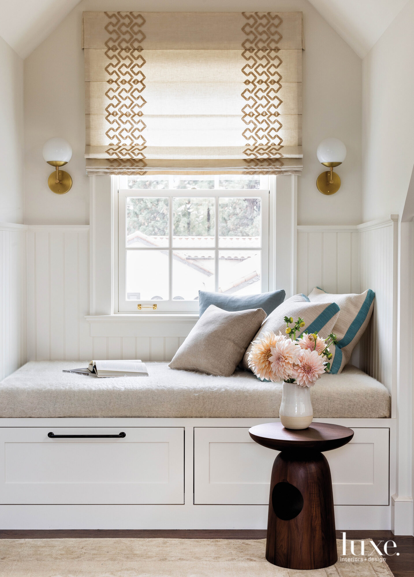 Detail of seating nook in family room covered with pillows in front of a bright window.