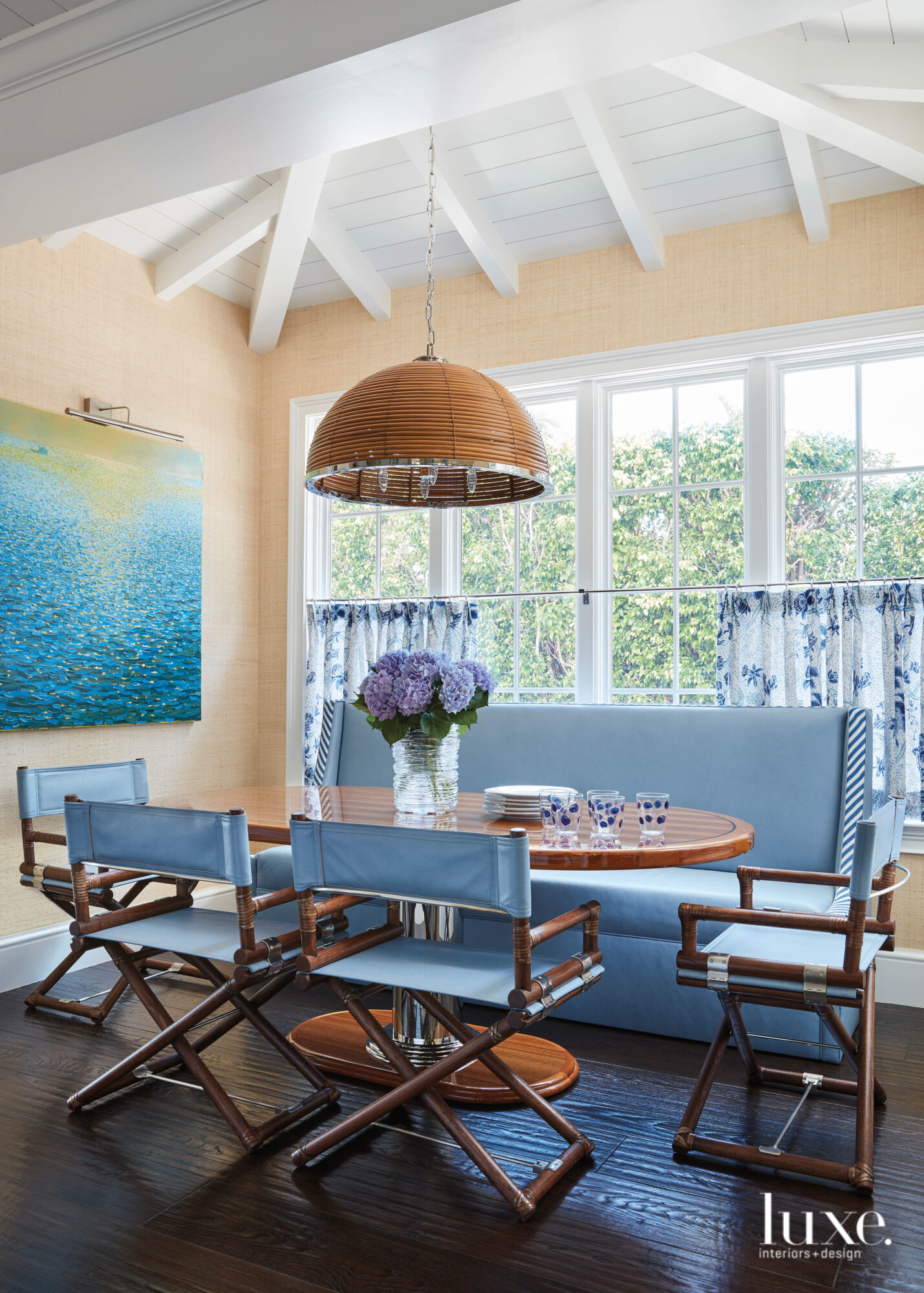 Breakfast nook with periwinkle-blue leather chairs beneath a reeded light fixture.