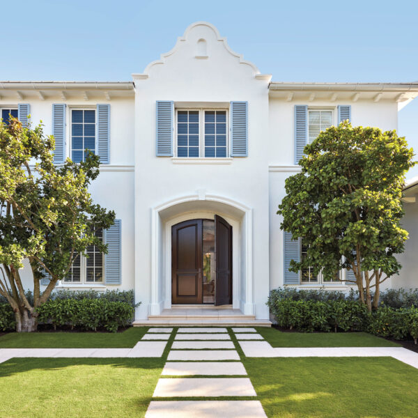 With Palm Frond Accents And Dominant Blue Tones, This Palm Beach Getaway Shines With Island Glamour Exterior of white home with light blue shutters and a mahogany door.