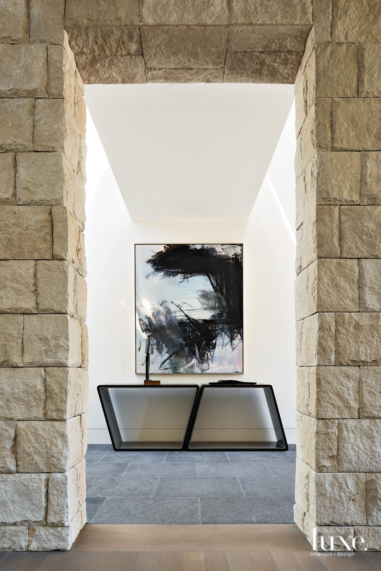 A geometric console sits beneath an abstract painting.