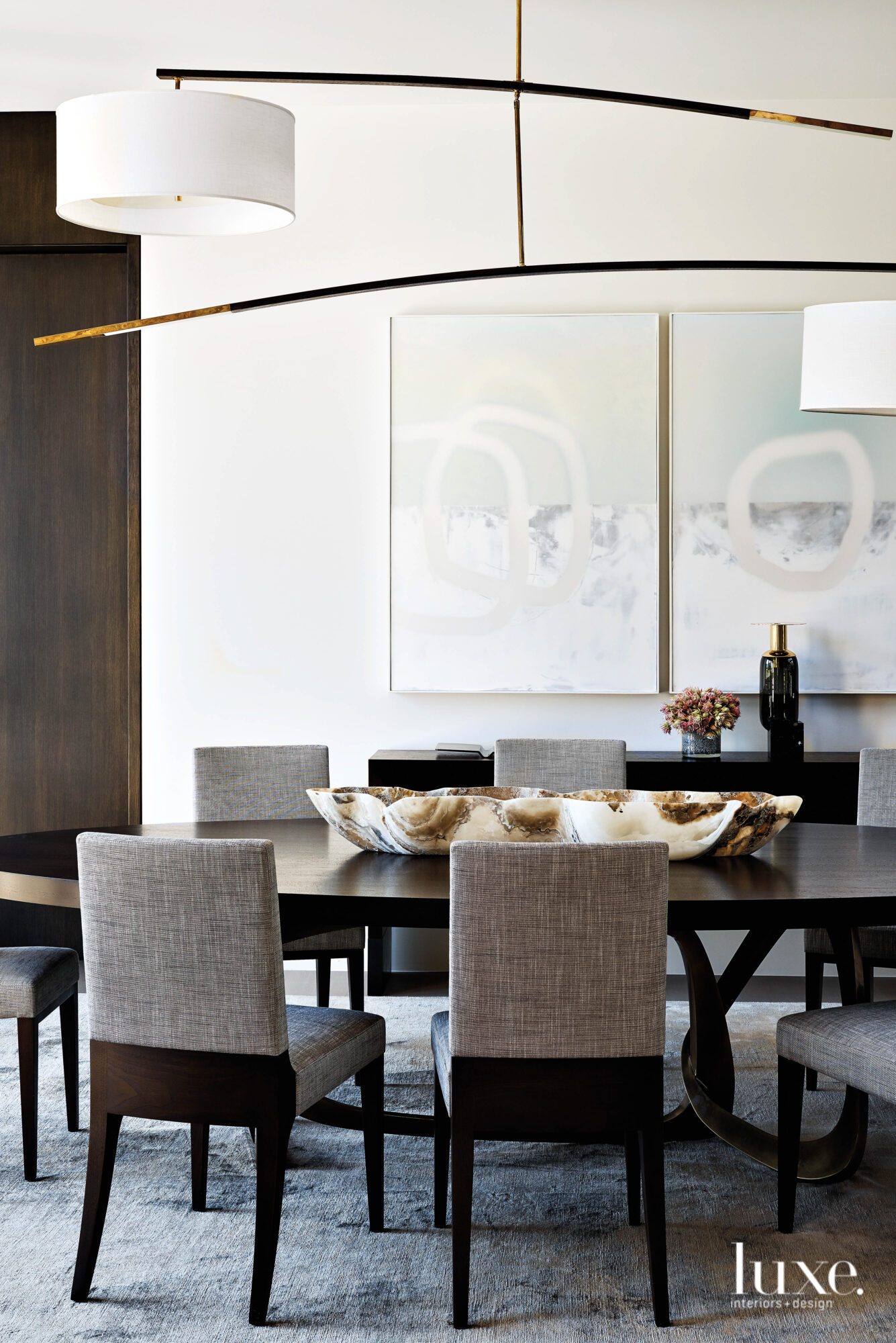 In the dining room, a large, sculptural light fixture hangs over a table and zebra print chairs.