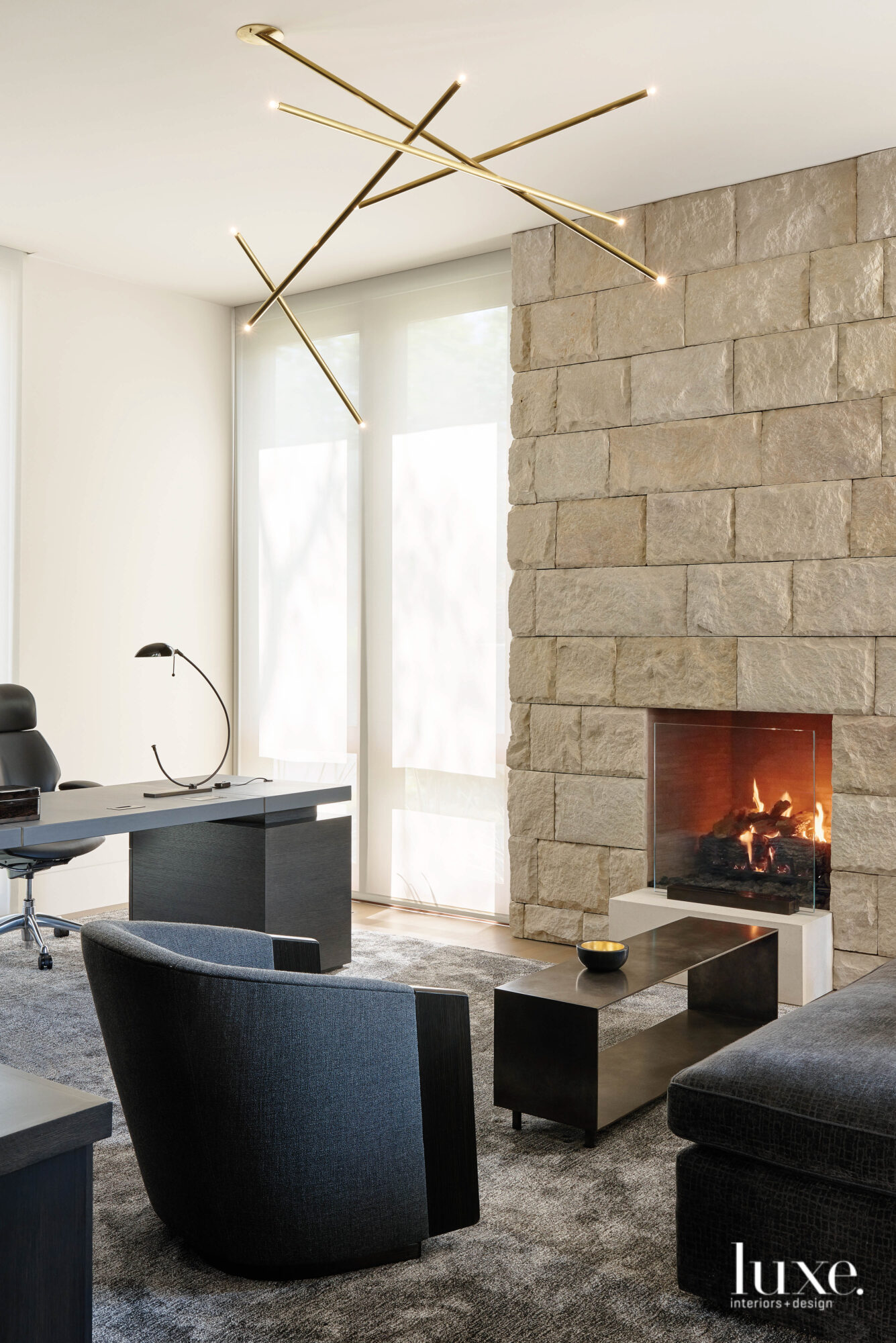 A fireplace nook is carved out in the accented stone wall in this home office space.