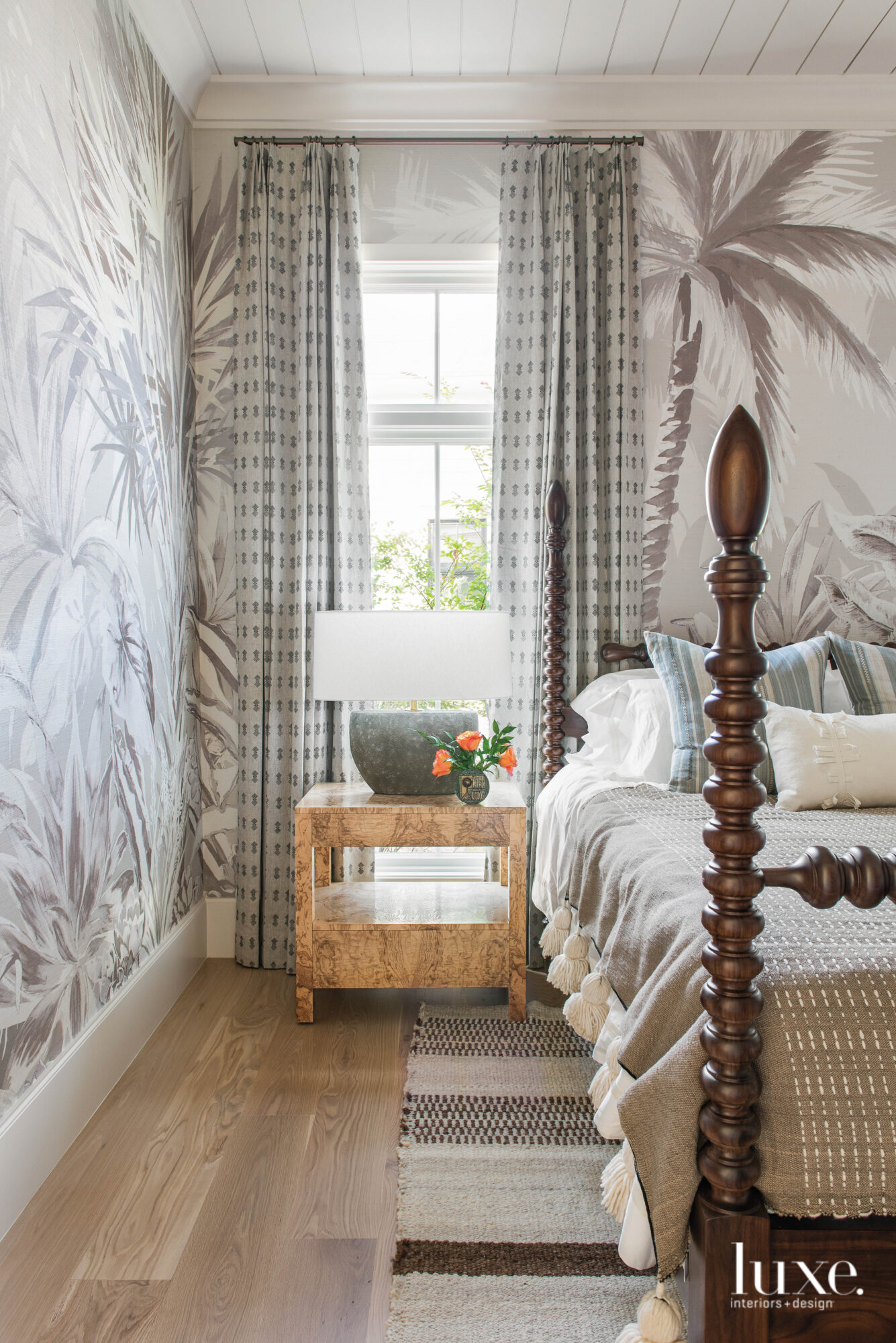 Four-poster bed with tall window and palm-print wall covering