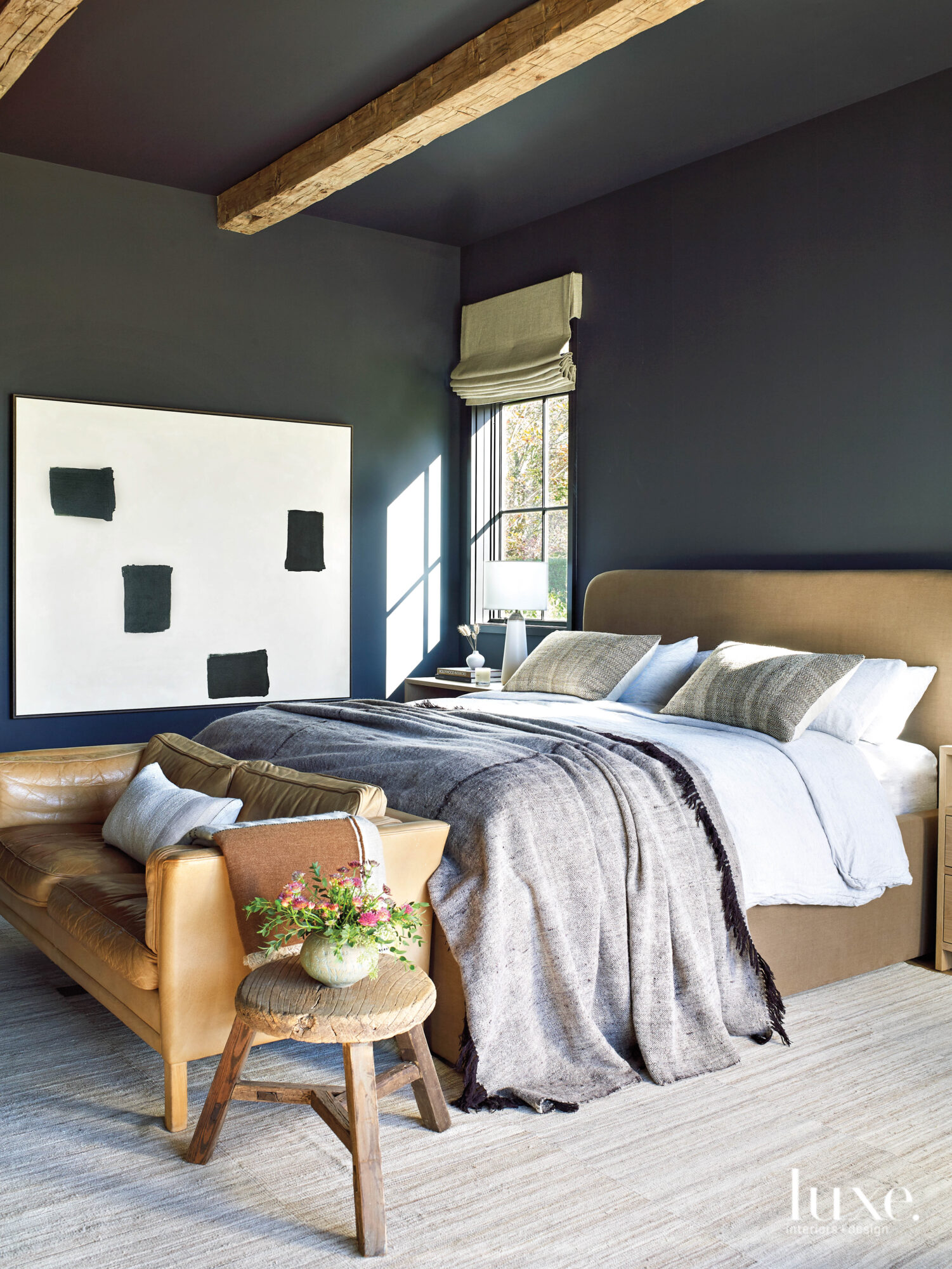 Abstract art and a small leather couch sit in the master bedroom