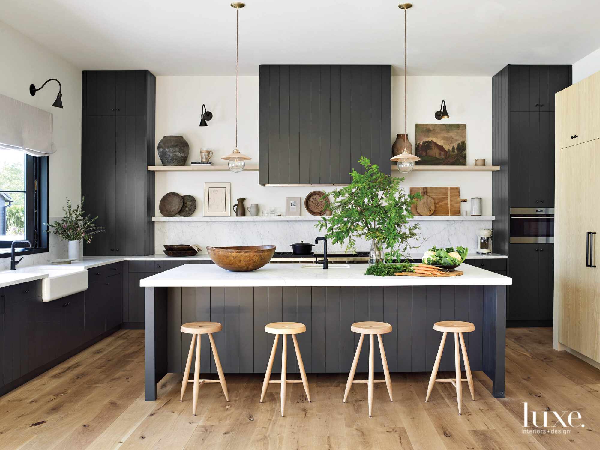 Small barstools sit in a kitchen defined by black cabinetry