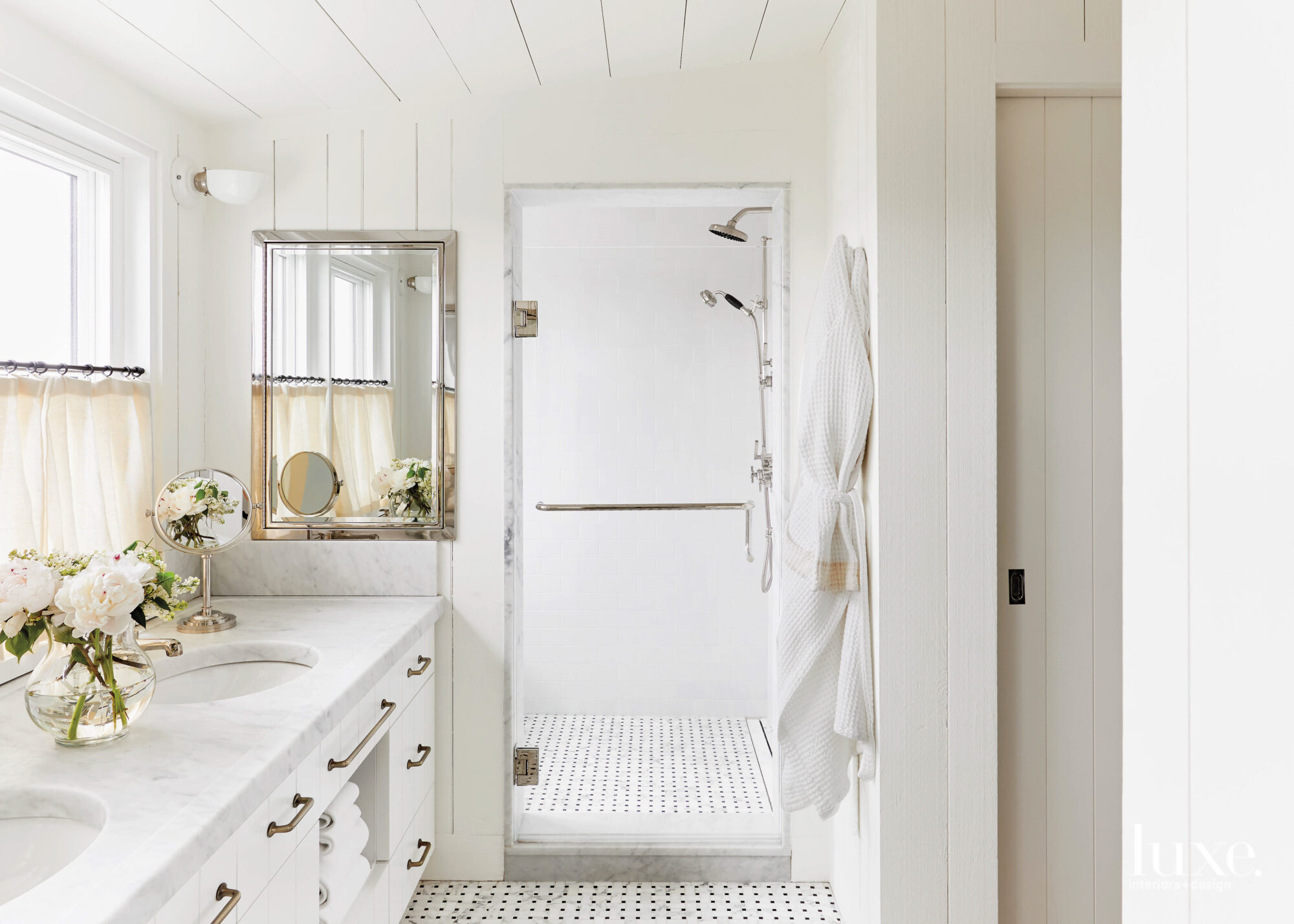 Brassy finishes add a pop to the all-white master bathroom