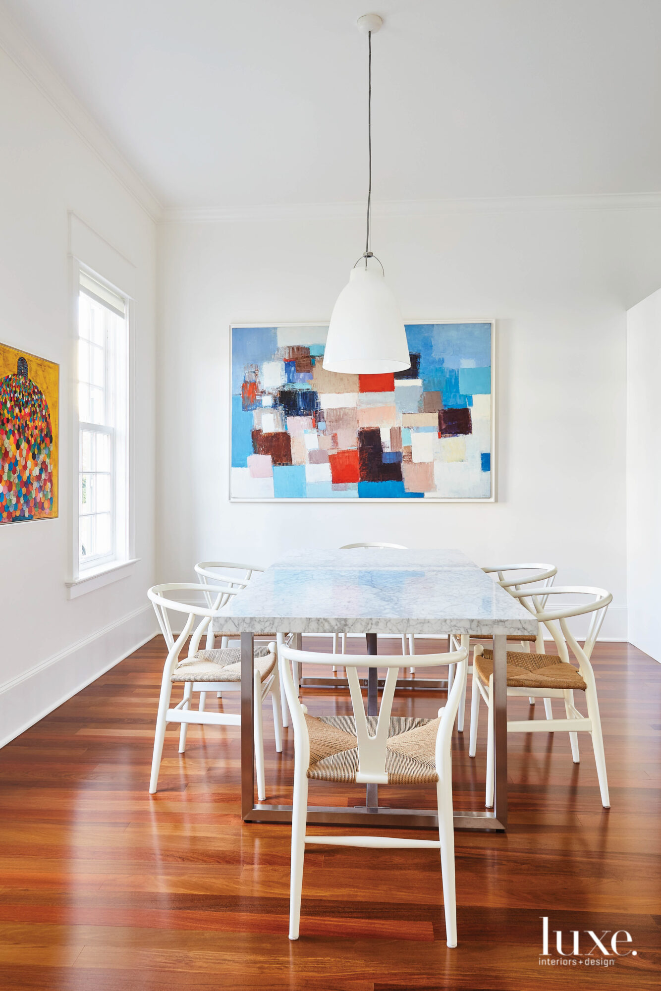 Dining room with marble and stainless steel table and colorful abstract art.