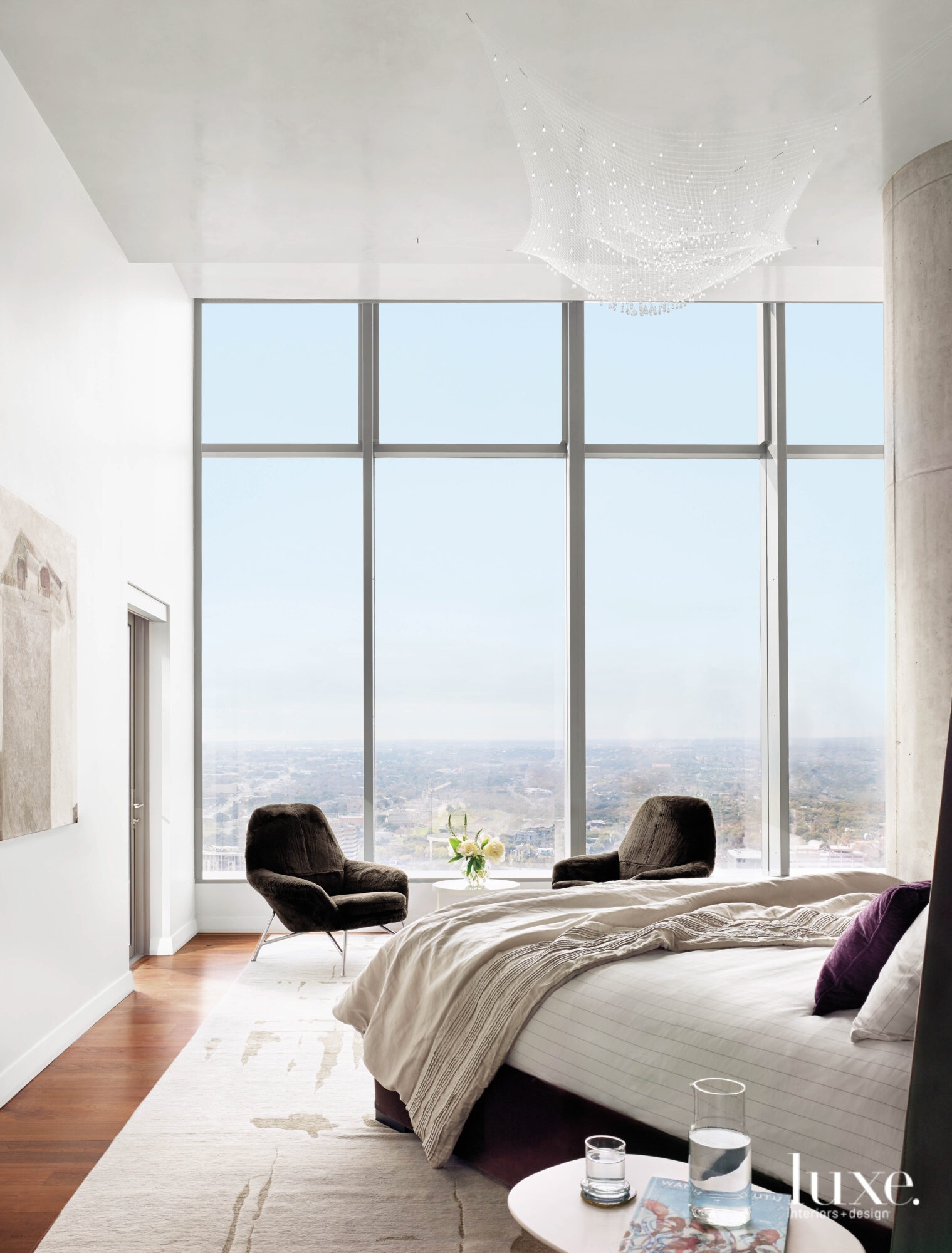 A serene bedroom with statement art and large windows.