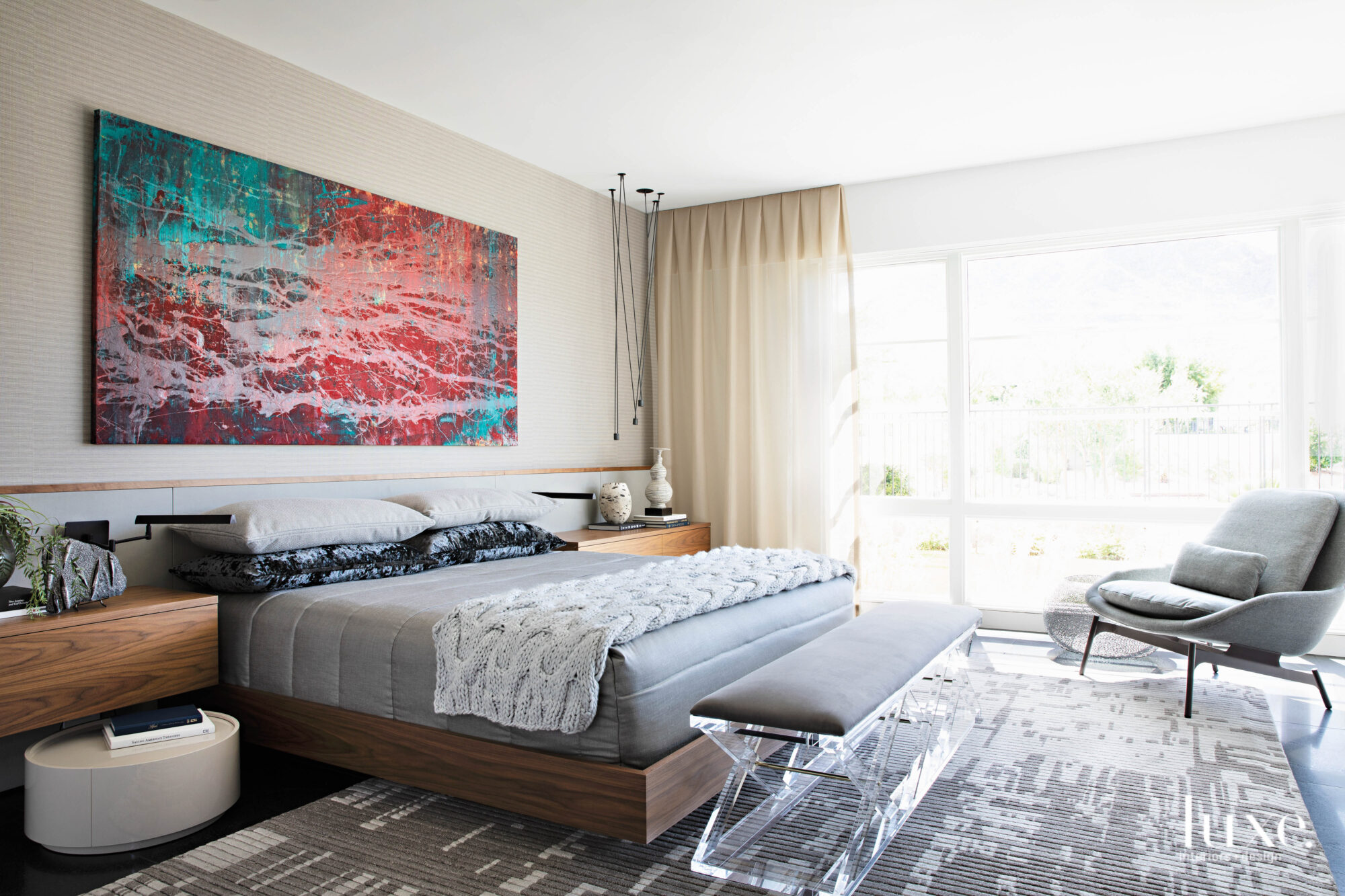 A bright red-and-turquoise abstract painting hangs above the bed in the otherwise neutral master bedroom.