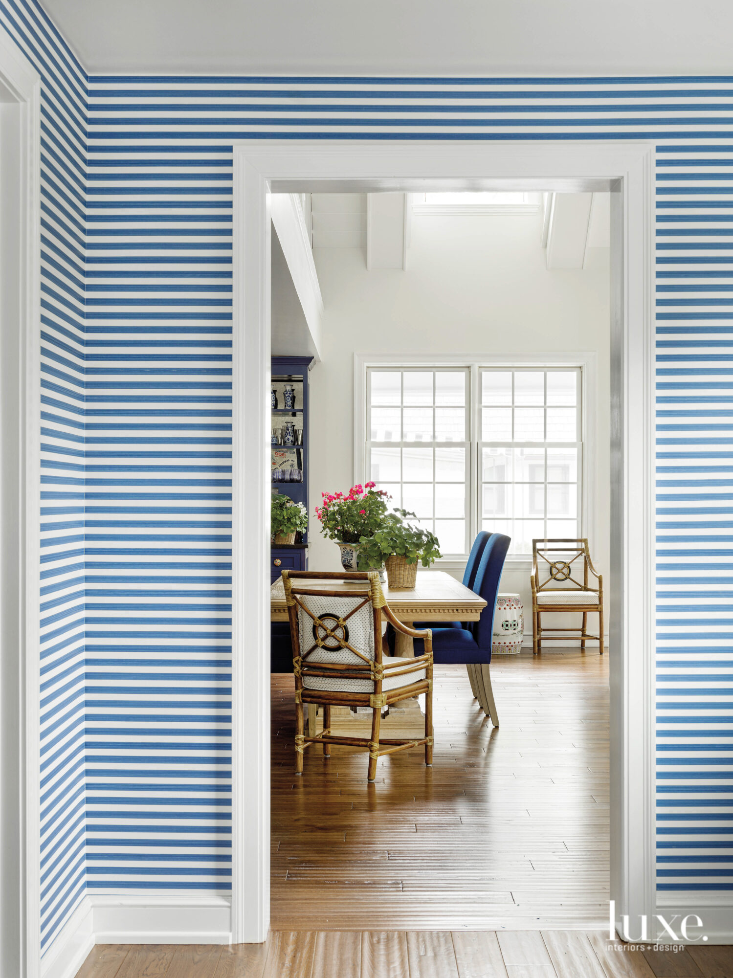 The hallway that looks into the kitchen has blue-and-white striped wallpaper.