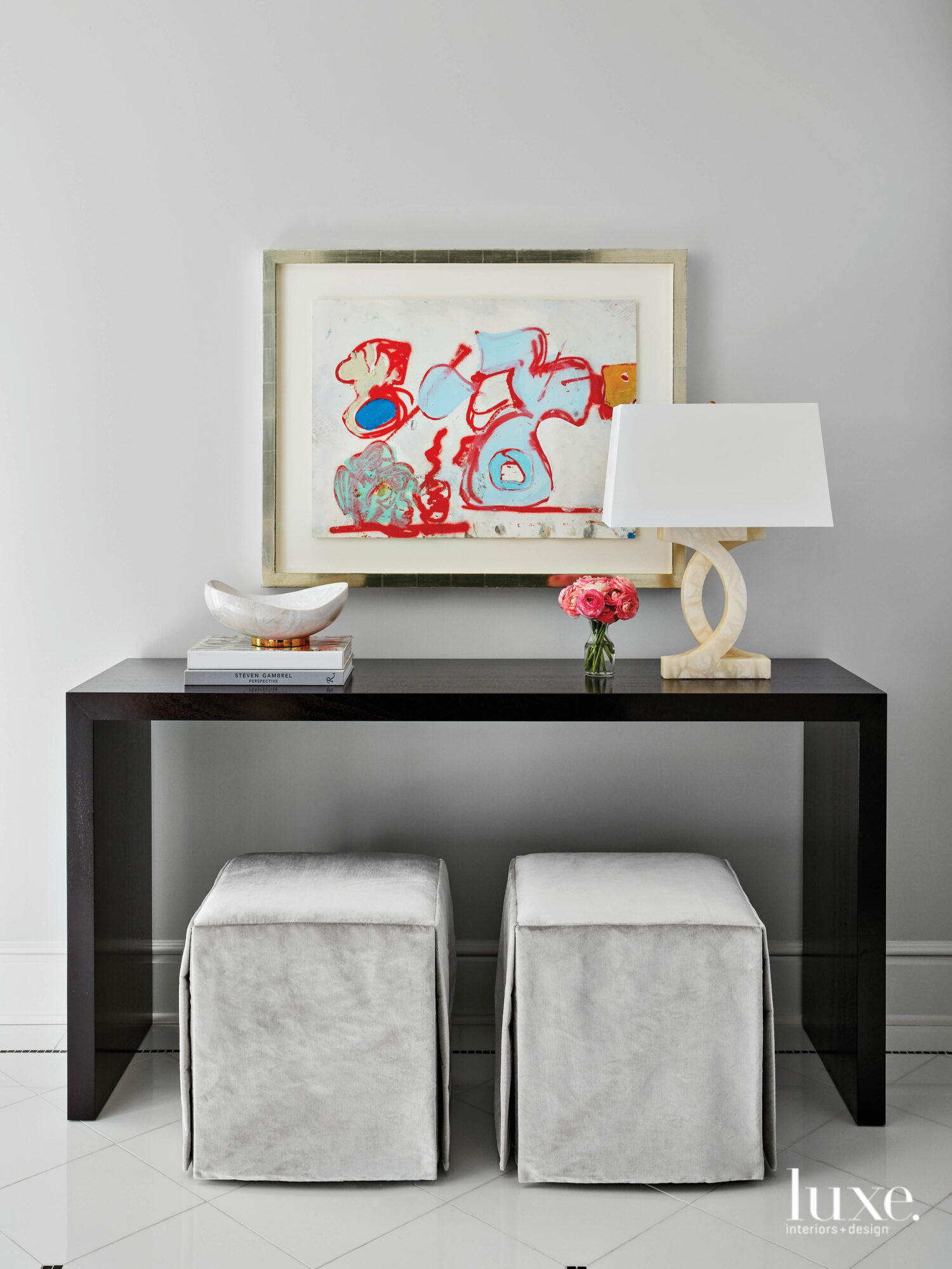 The entry foyer with a black console, gray upholstered stools and a bright Eddie Martinez painting.