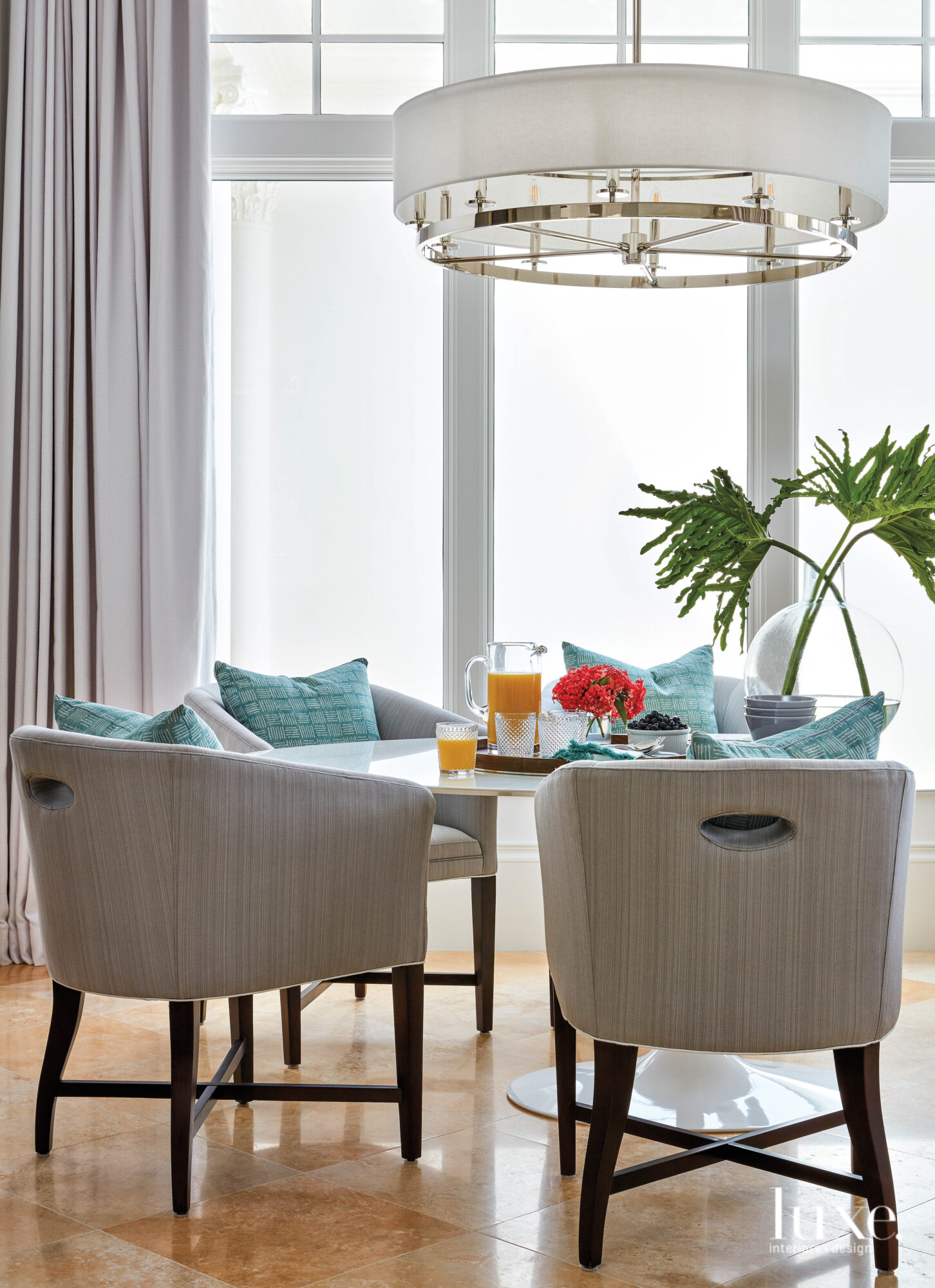 Breakfast room with gray chairs and turquoise pillows.