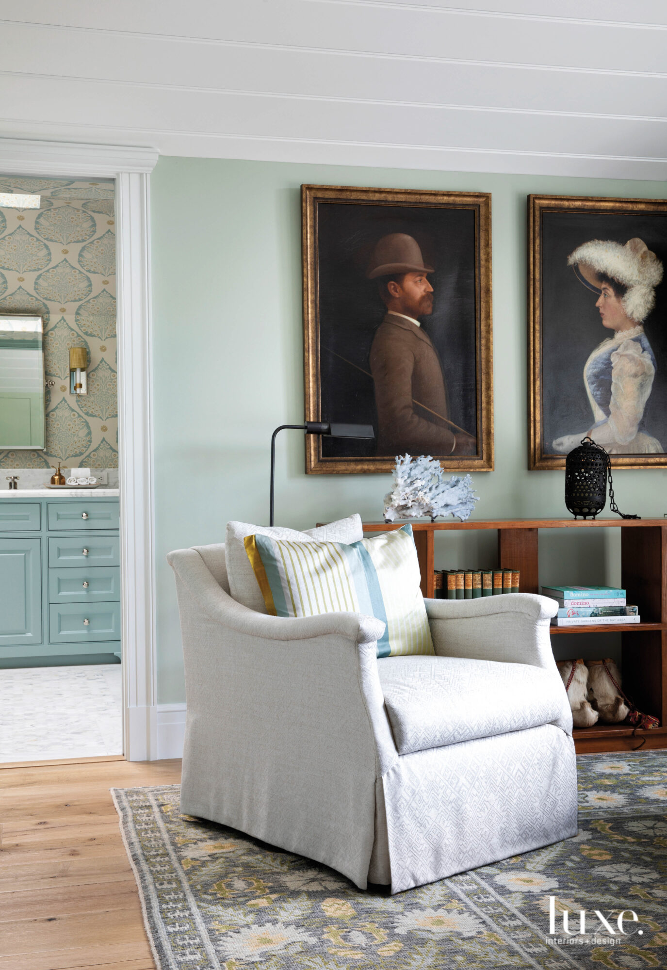 Two portraits of a male and female and a comfortable armchair are found in the master bedroom.
