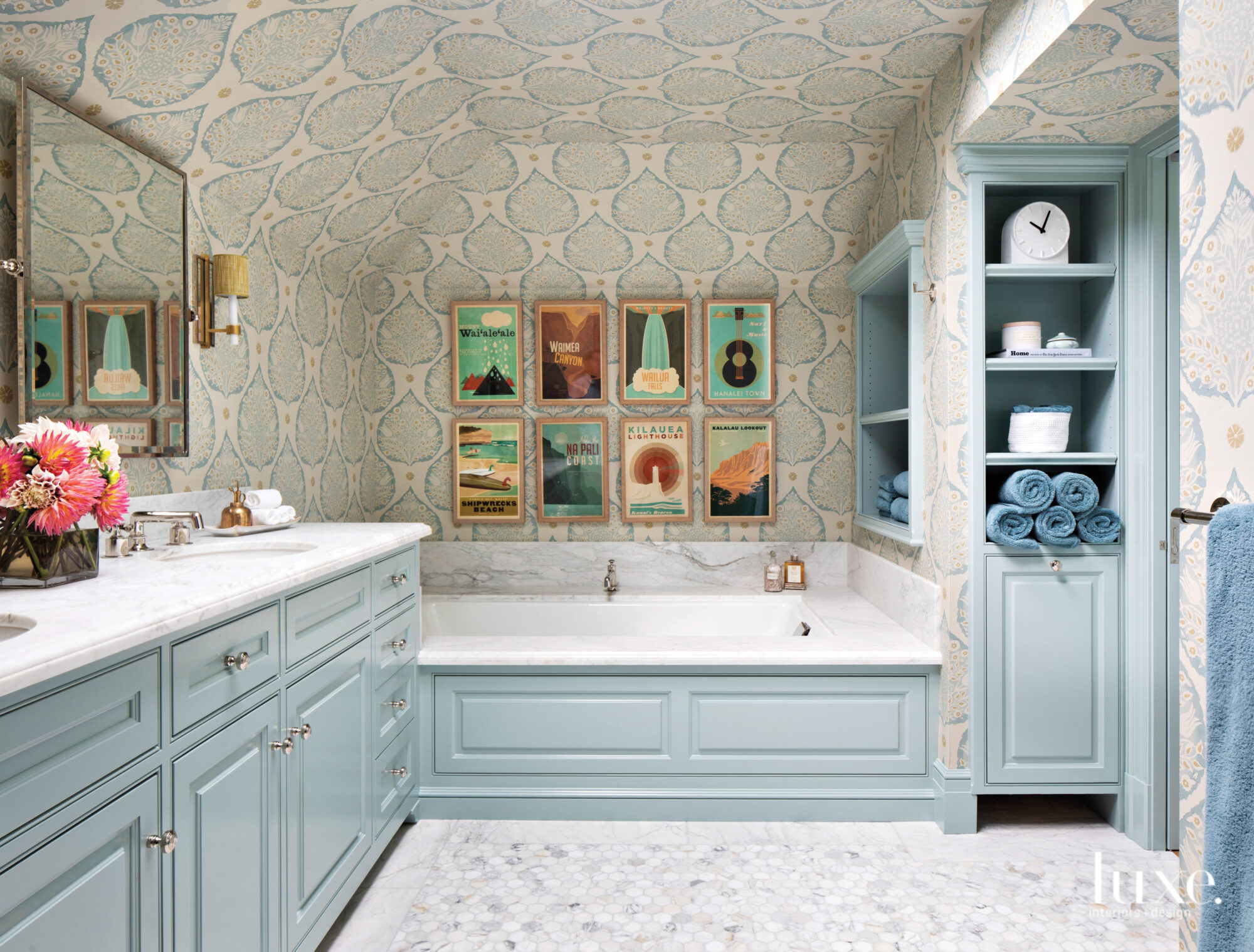 In the primary bathroom, a charming collection of vintage prints hang above the tub. The cabinetry is light blue.
