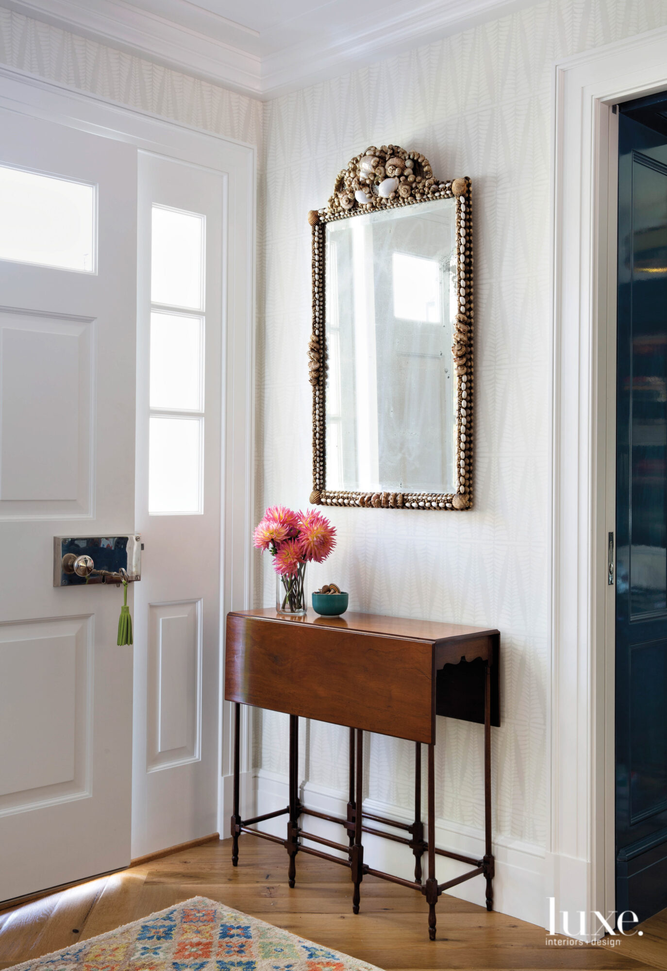 In the entry, a shell-studded mirror hangs above a small wooden table.