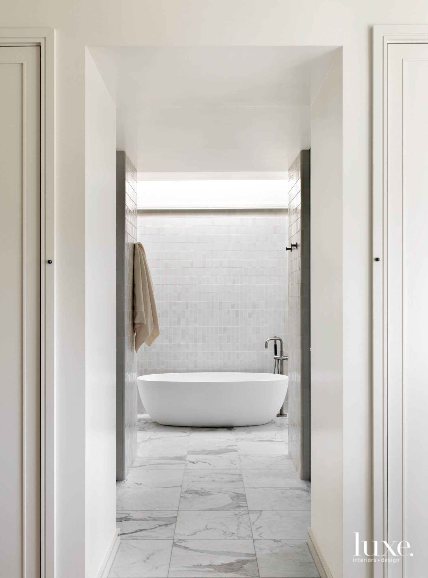 The primary bath is all white tile and stone.