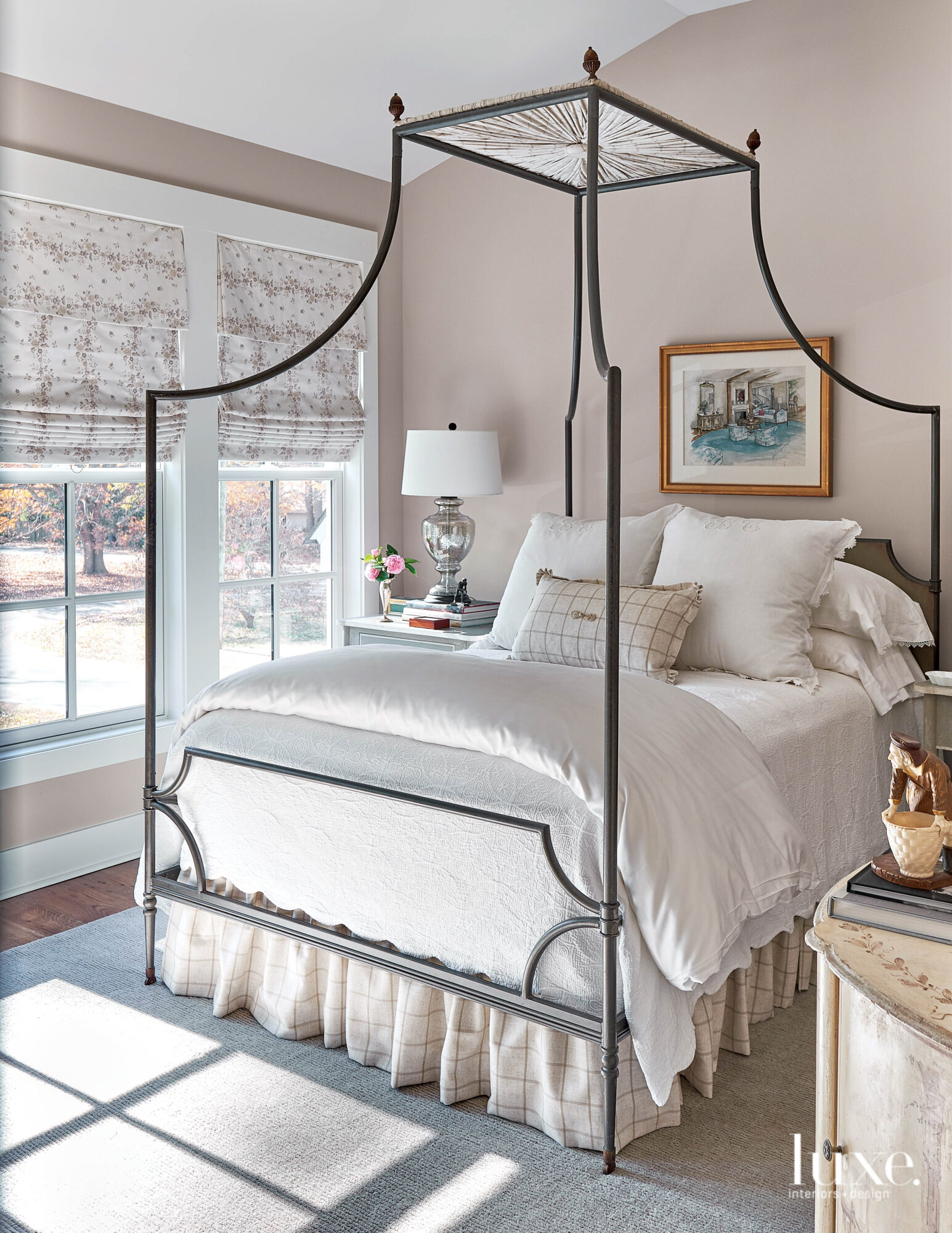 Bedroom with light neutral walls, iron canopy bed and gathered bed skirt